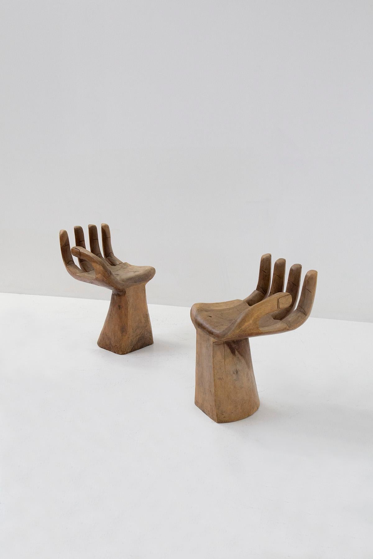 Eccentric pair of hand-shaped chairs made entirely of wood from the 1980s. The pair of chairs are in the style of Pedro Friedeberg, as in his creation these pair of chairs take up the design of hands creating an eccentric seat. The seat is carved