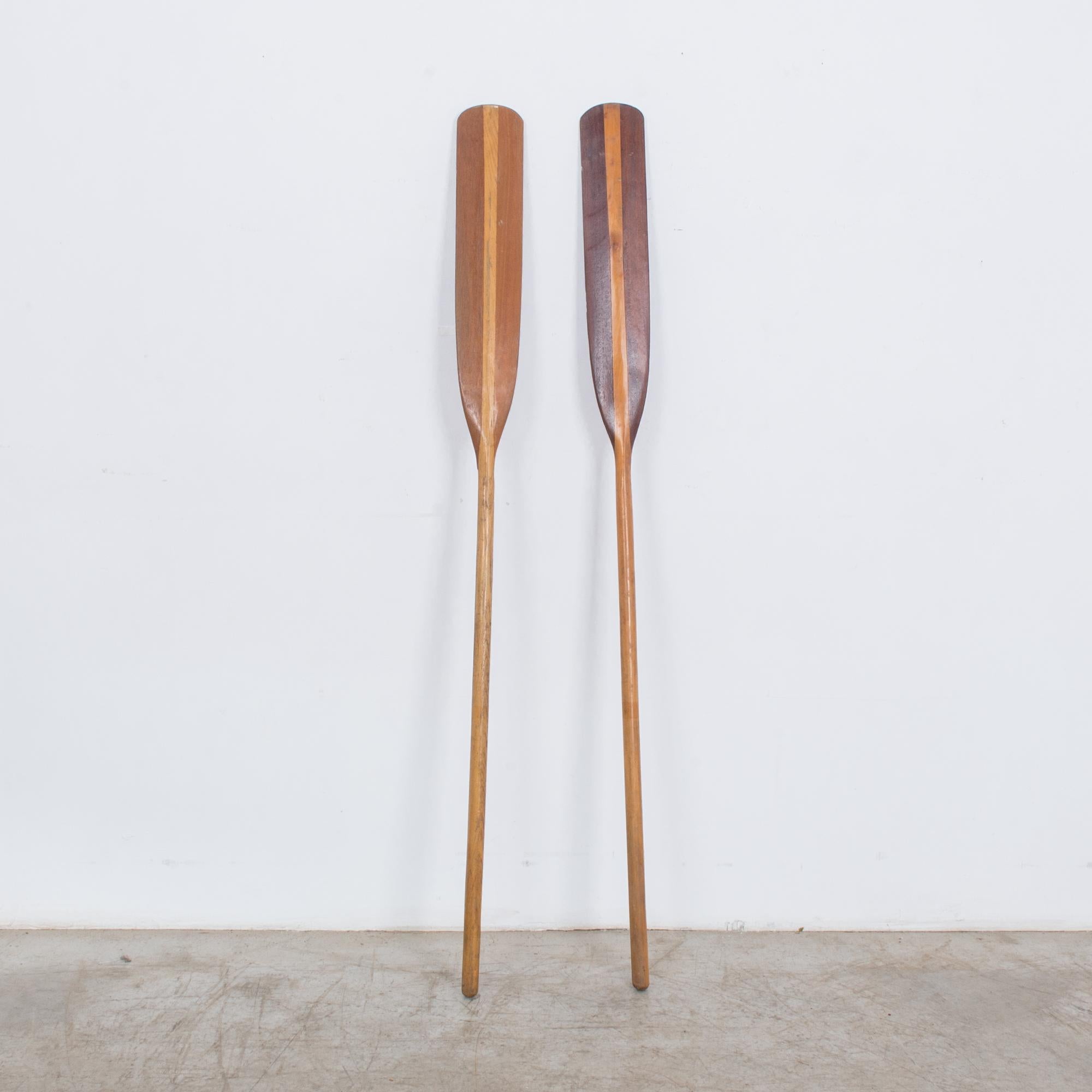 This pair of wooden boat oars was made in France, circa 1960.
The polished wood has a smooth finish with a dual-toned blade and a light brown shaft. Perfect for hanging on the wall, the oars will complete a beach house or impart the charm of an