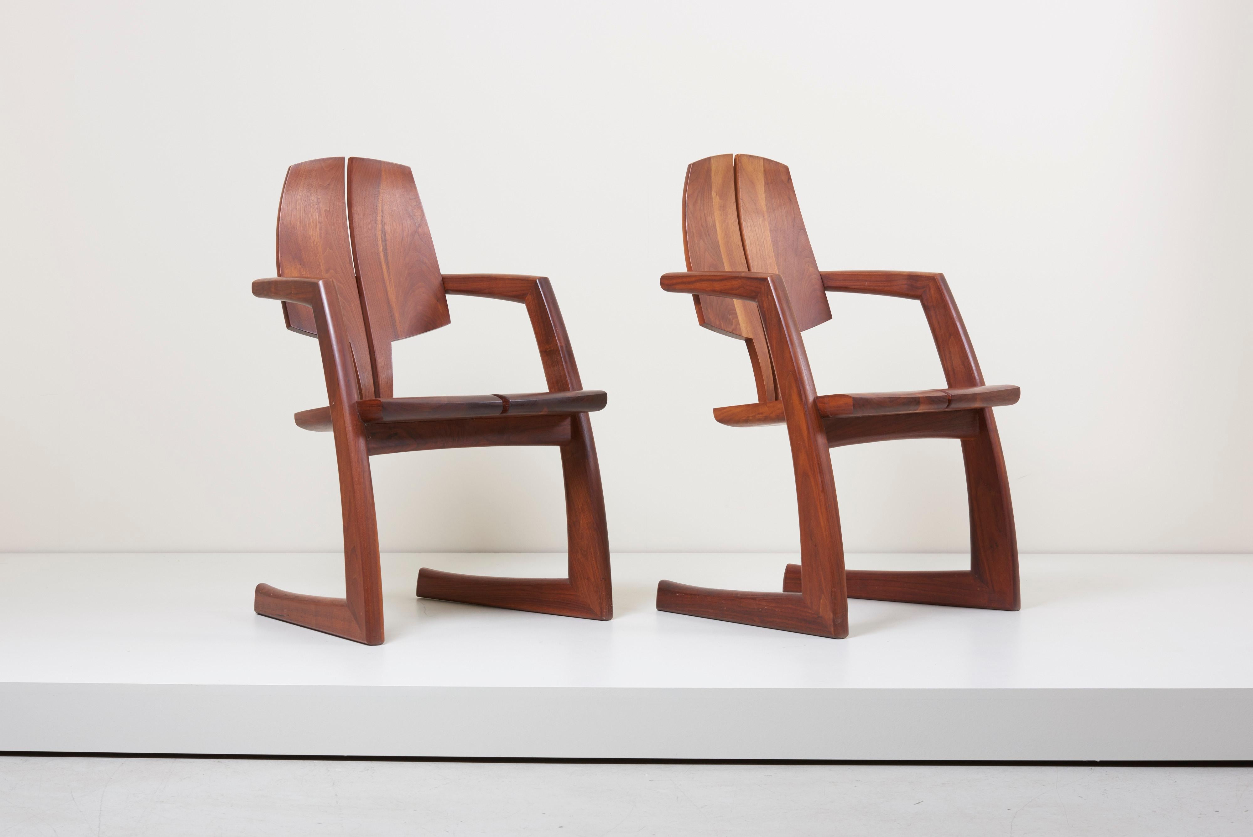This pair of wooden American craft chairs is designed by Woodworker H. Wayne Raab. The chairs have an individual design and are made of solid walnut. They are heavy, solid, and very well made, with no looseness or wobbliness. Excellent original