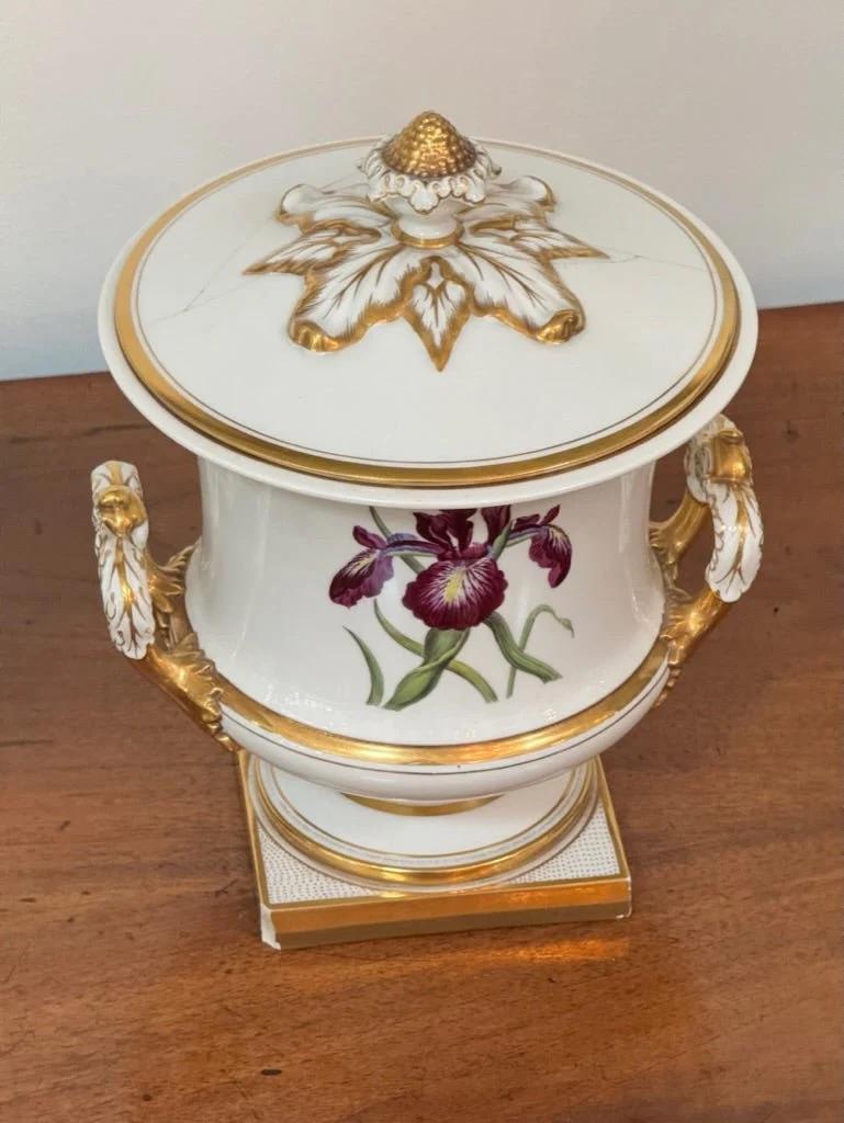 Pair of Worcester Porcelain Covered Fruit Coolers Circa 1813.  The painted waists of violets, morning glories, roses, and crabapple blossoms within a gilt border flanked by burnished parcel-gilt handles on socle and square base. 

