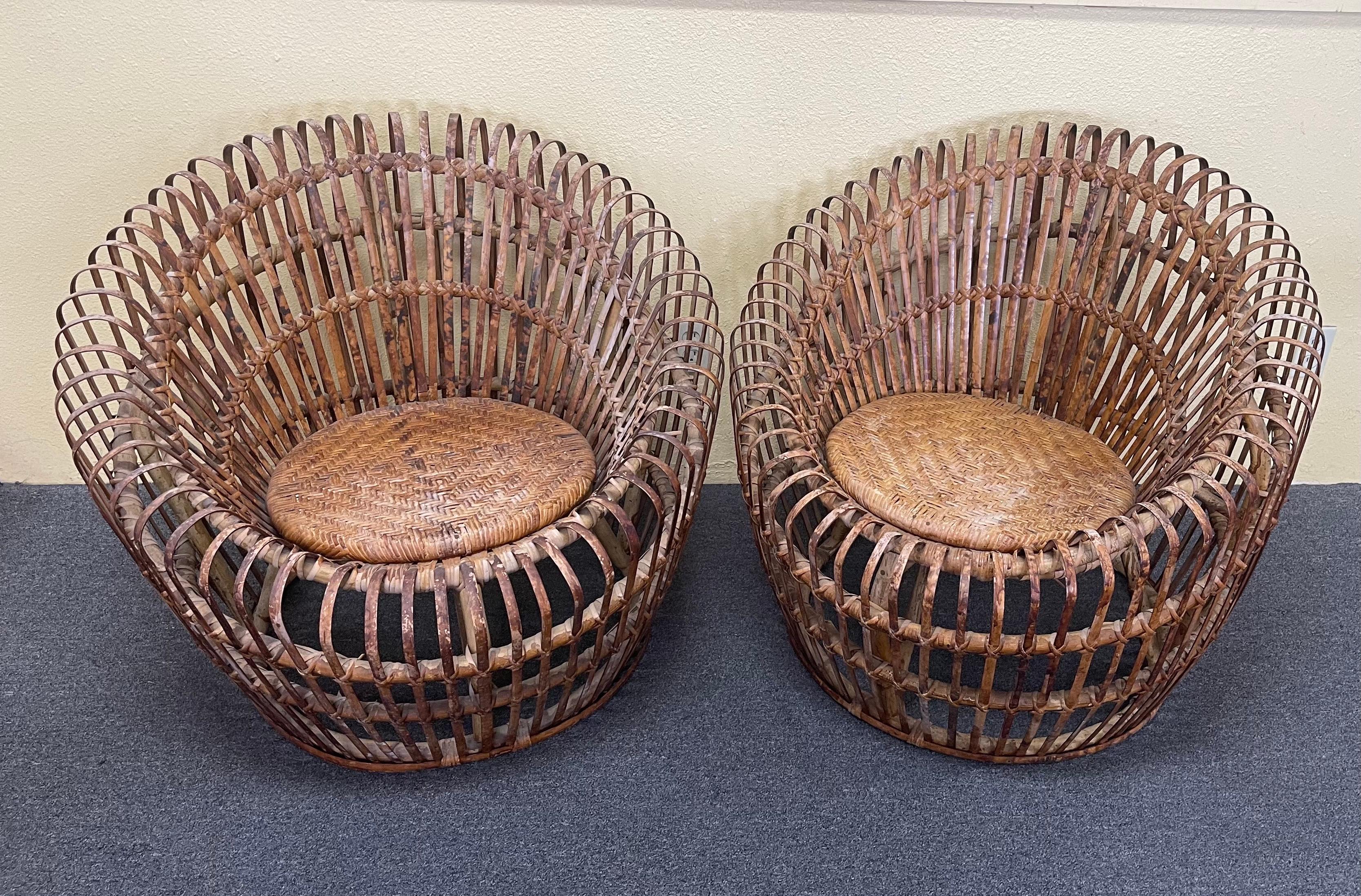 Pair of woven bamboo / rattan lounge chairs in the style of Franco Albini, circa 1950s. These wonderful vintage chairs have a woven seat, bent tortoise colored reed and a very cool round style that makes the chairs so appealing. They are very light,