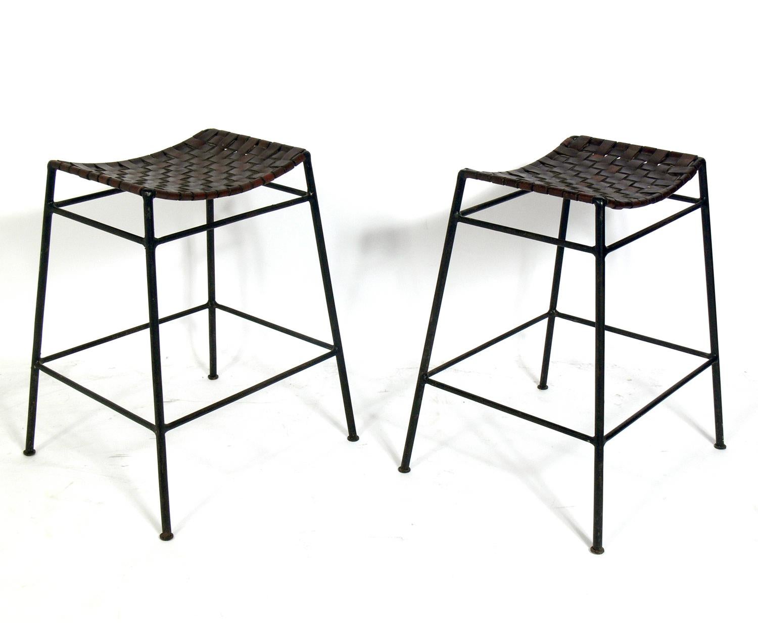 Pair of woven leather and iron bar stools, in the manner of Lila Swift and Donald Monell, believed to be circa 1980s. Wonderful original patina to the woven leather seats and iron frames.