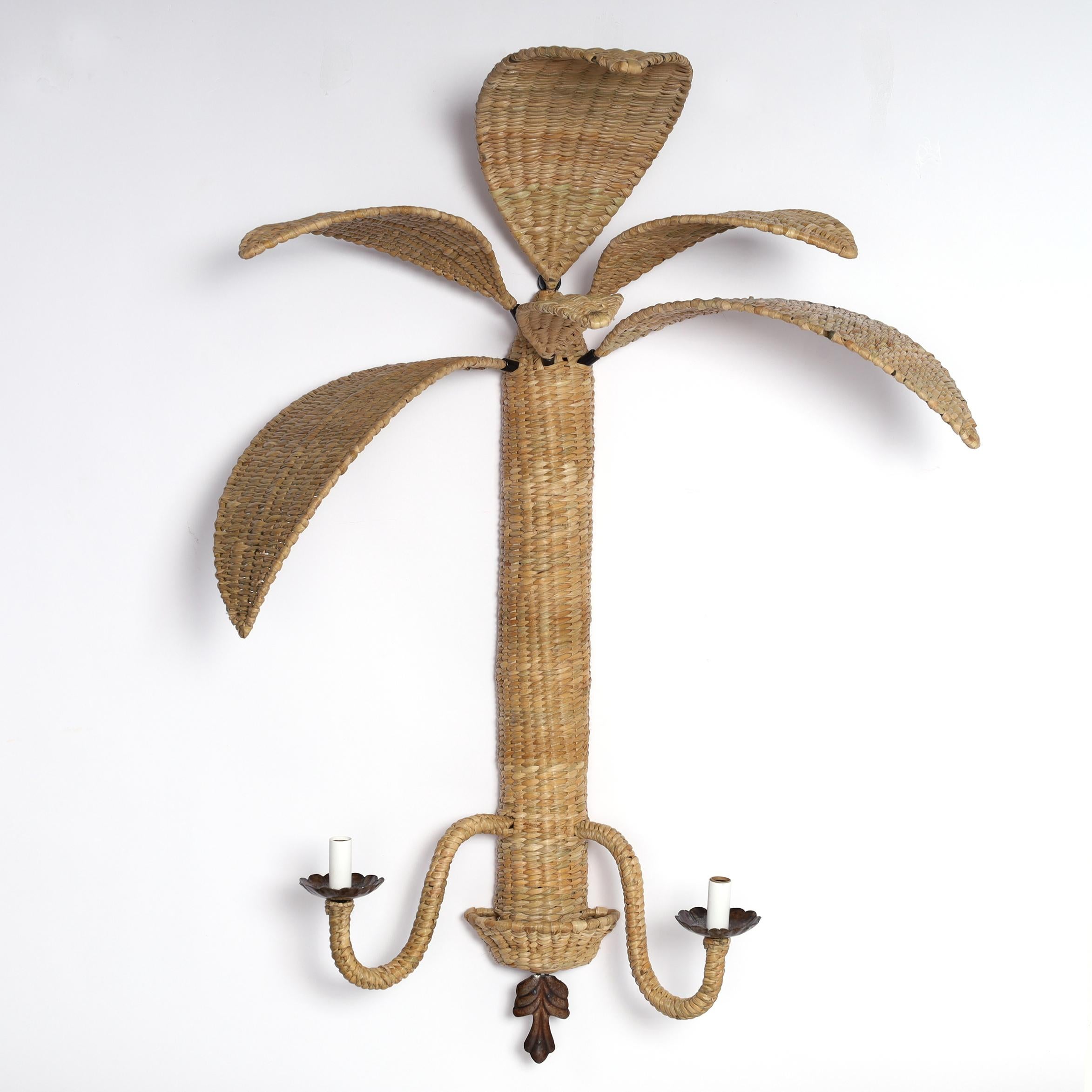 Inspired pair of two light wicker wall sconces handcrafted with a metal frame under woven reed in a casually elegant palm tree form with removable leaves. Designed and manufactured exclusively by F S Henemader Antiques. 