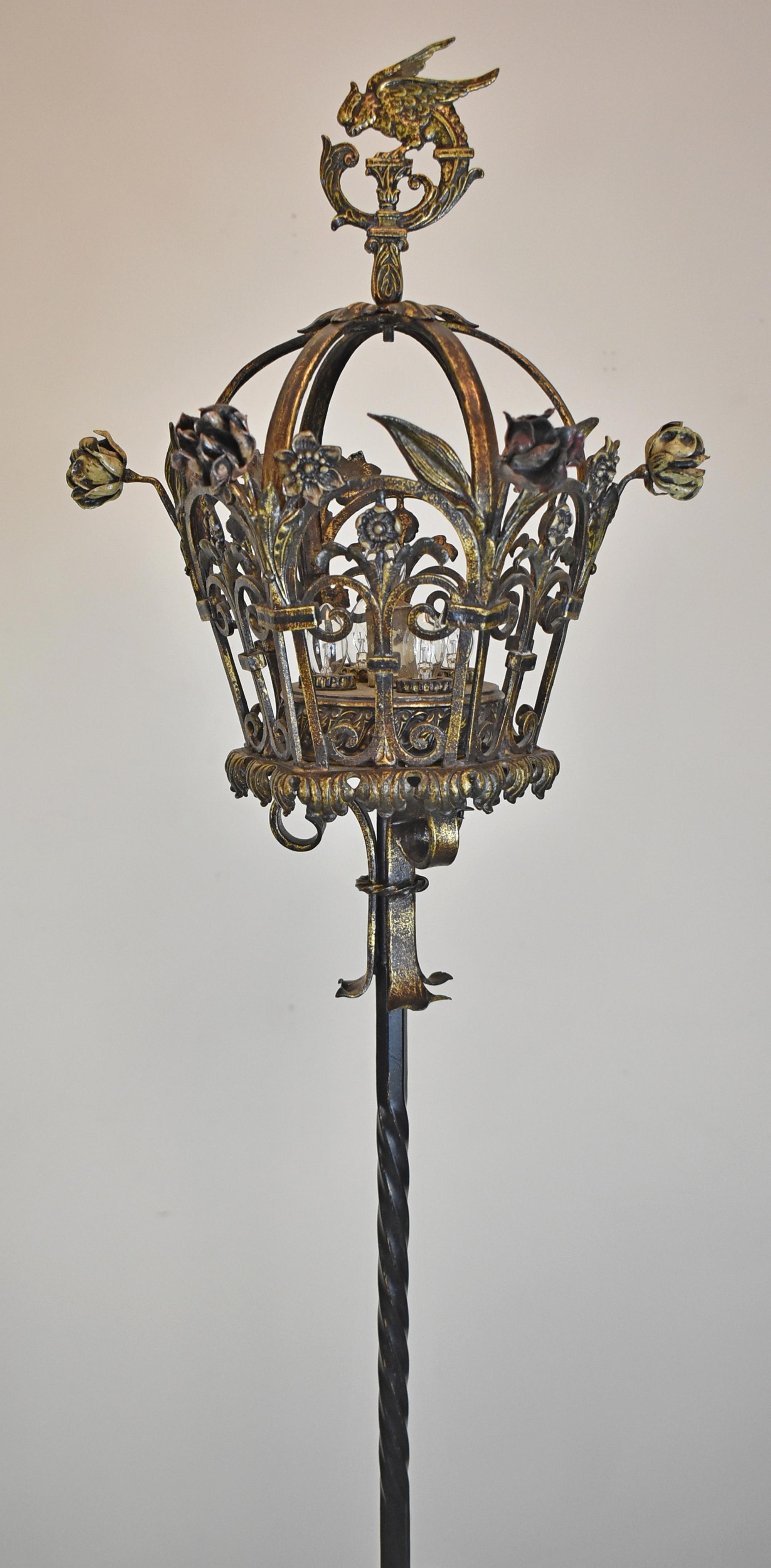 Pair of gold and charcoal wrought iron torchier floor lamps circa 1910s-1920s. Figured marble base. Bird cage top with enameled floral details. Parrot finials. Each light takes five bulbs.