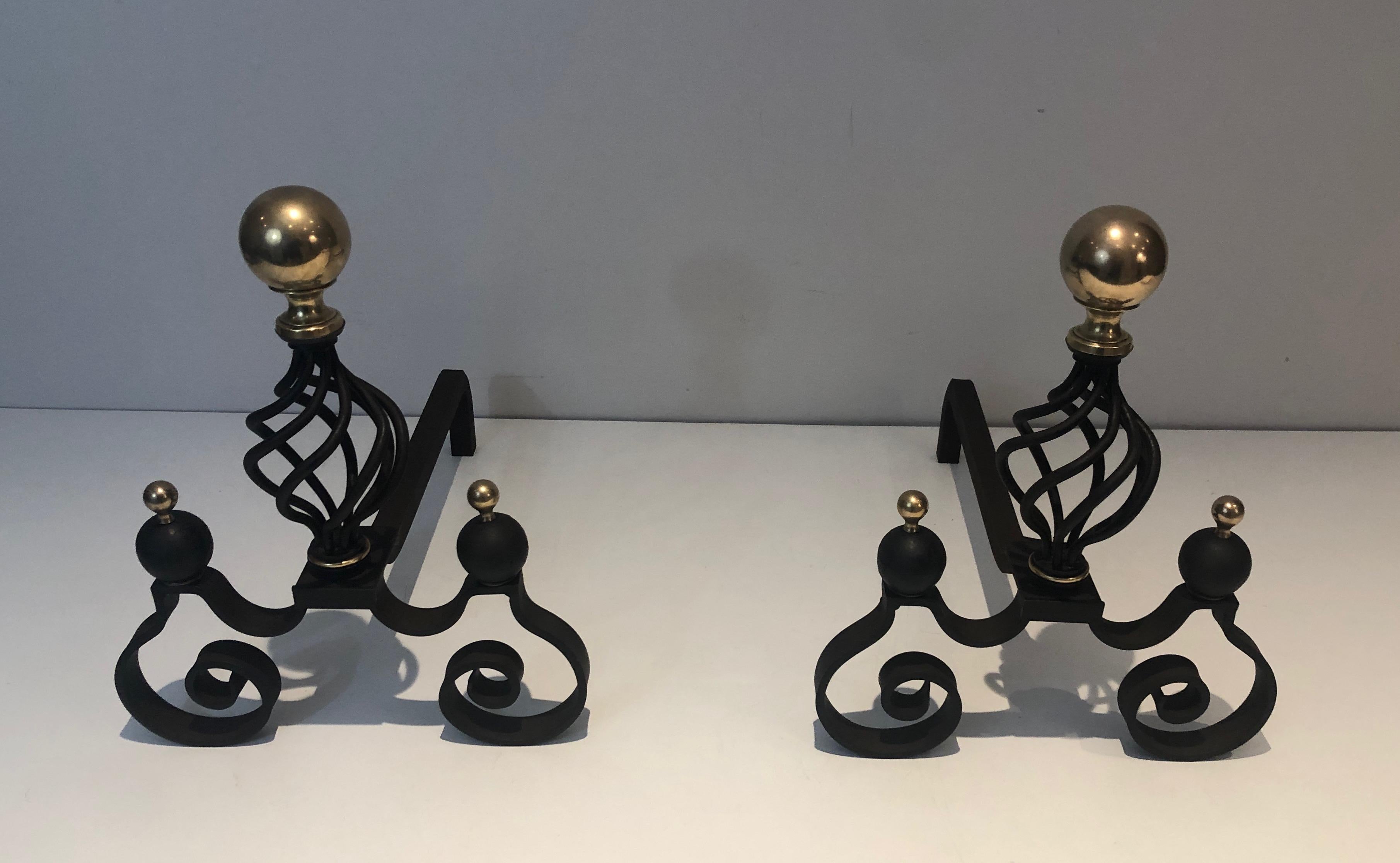 This very nice and unusual pair of andirons is made of a delicate twisted wrought iron work with brass bawls. This is a French work. Circa 1970
