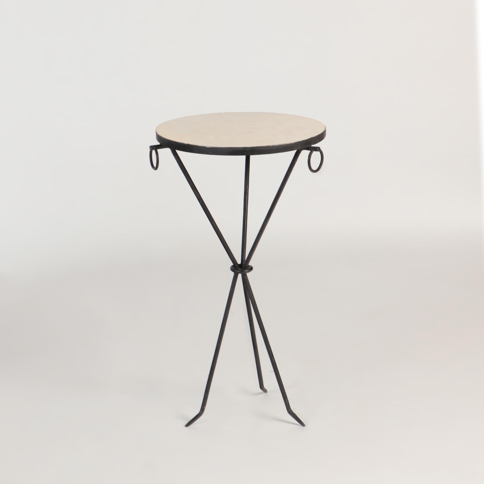 A pair of drinks tables composed of hand wrought iron with three brass ring decorations with parchment tops, in the manner of Jean-Michel Frank. The pieces have a sleek tripod form.
