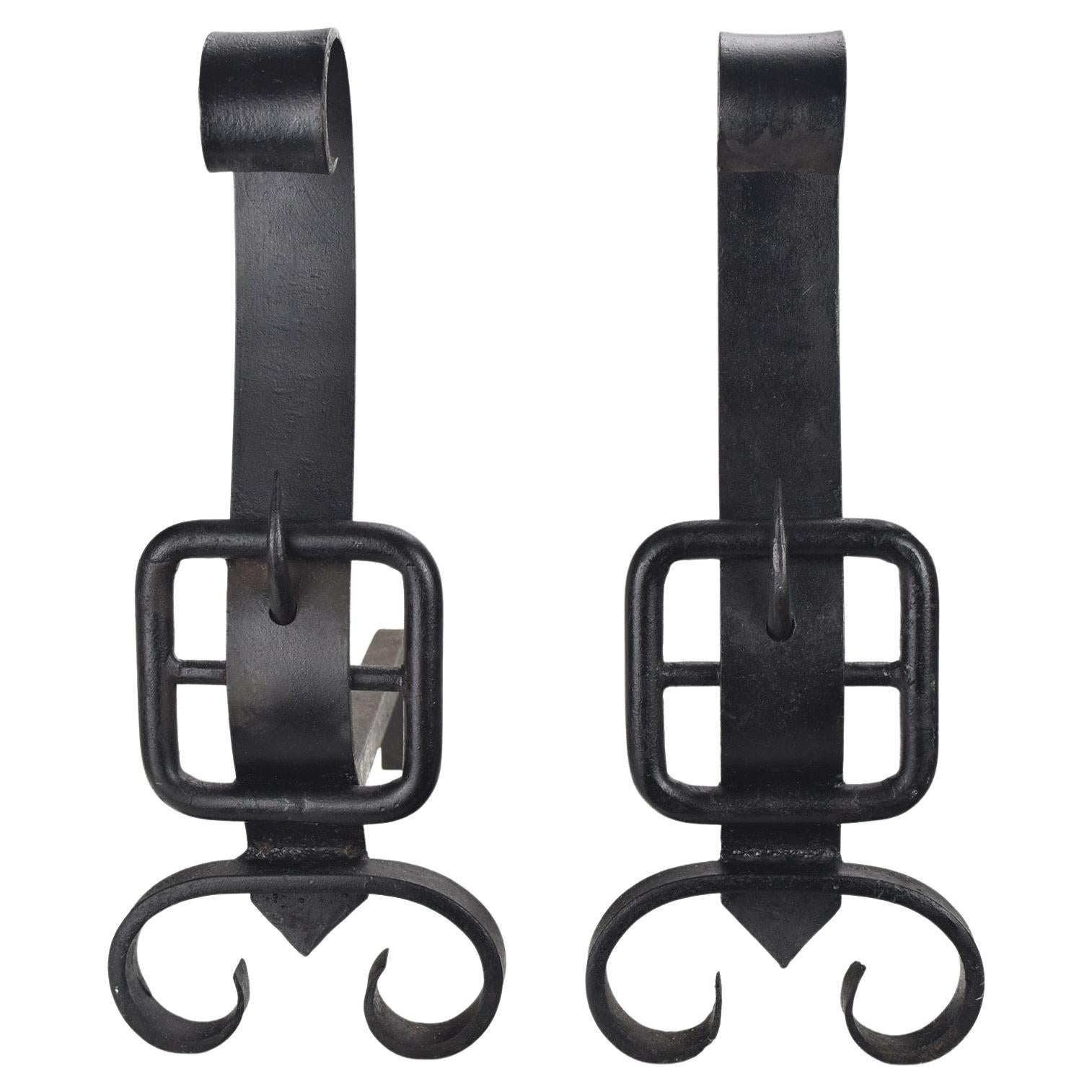 A highly decorative pair of large black patinated hand wrought iron andirons or firedogs in the manner of Jacques Adnet., marked with an unreadable artists signature.