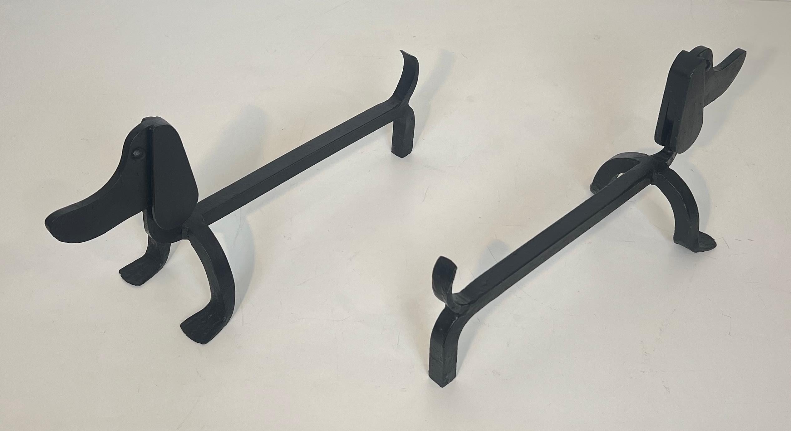 This nice and interesting pair of andirons is made of wrought iron. These firedogs represent dachshunds. This is a French work attributed to Edouard Schenck. Circa 1950