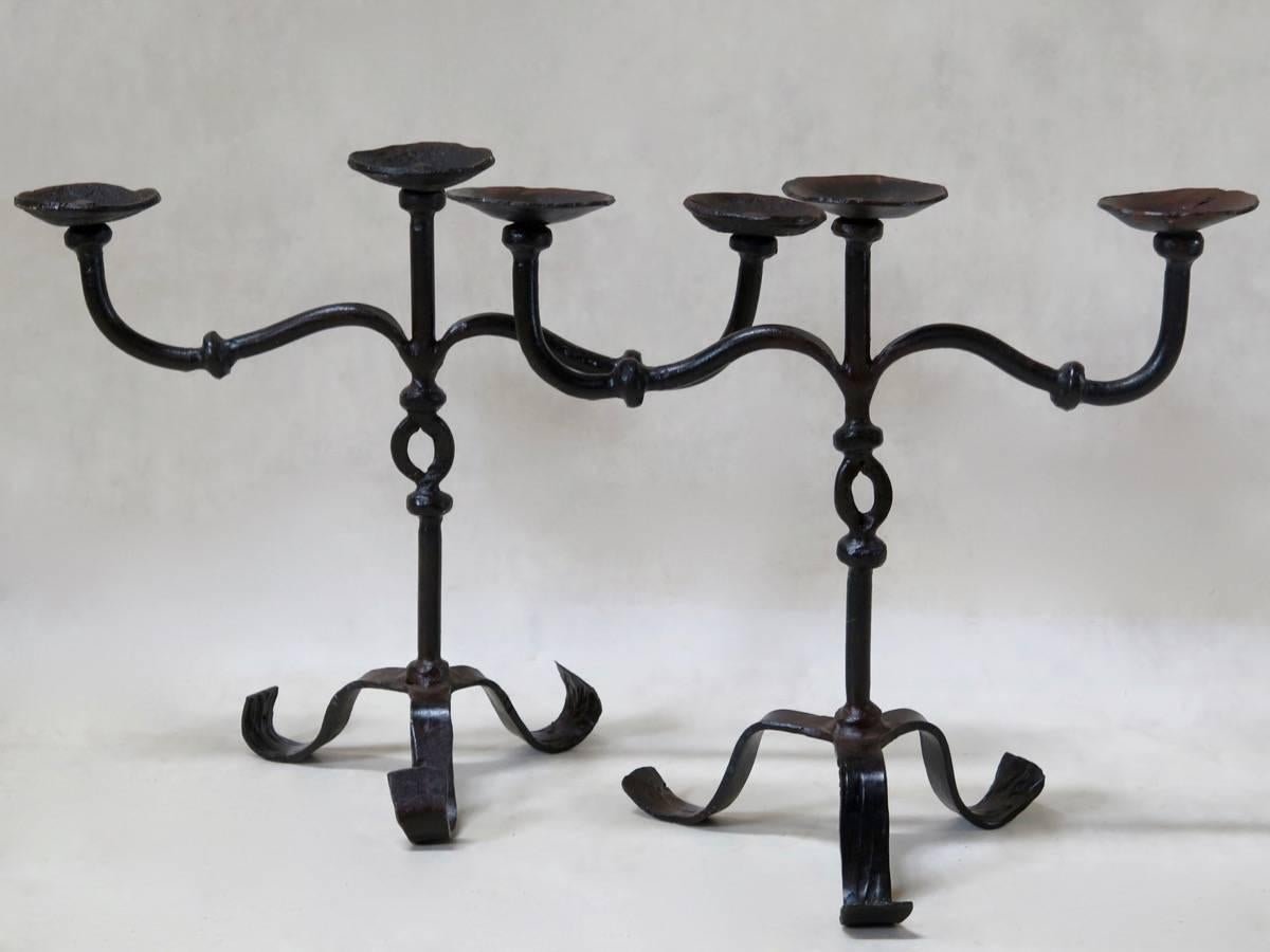 Pair of wrought iron three-arm Giacometti style candelabras raised on scrolled tripod feet with keyhole design on the stem.