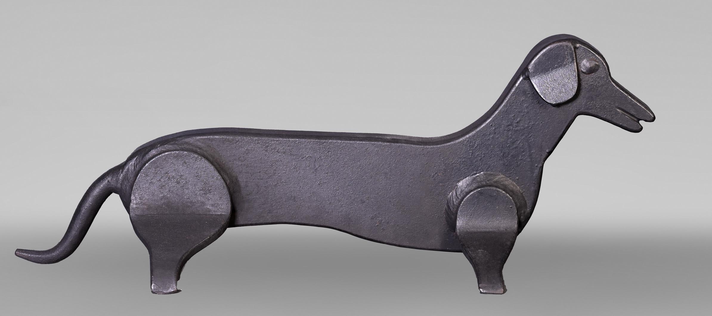Elegant and original, this pair of wrought iron andirons takes the form of charming stylized dachshunds. Their minimalist and geometric design highlights the elongated silhouette characteristic of this breed, while the subtly hammered details