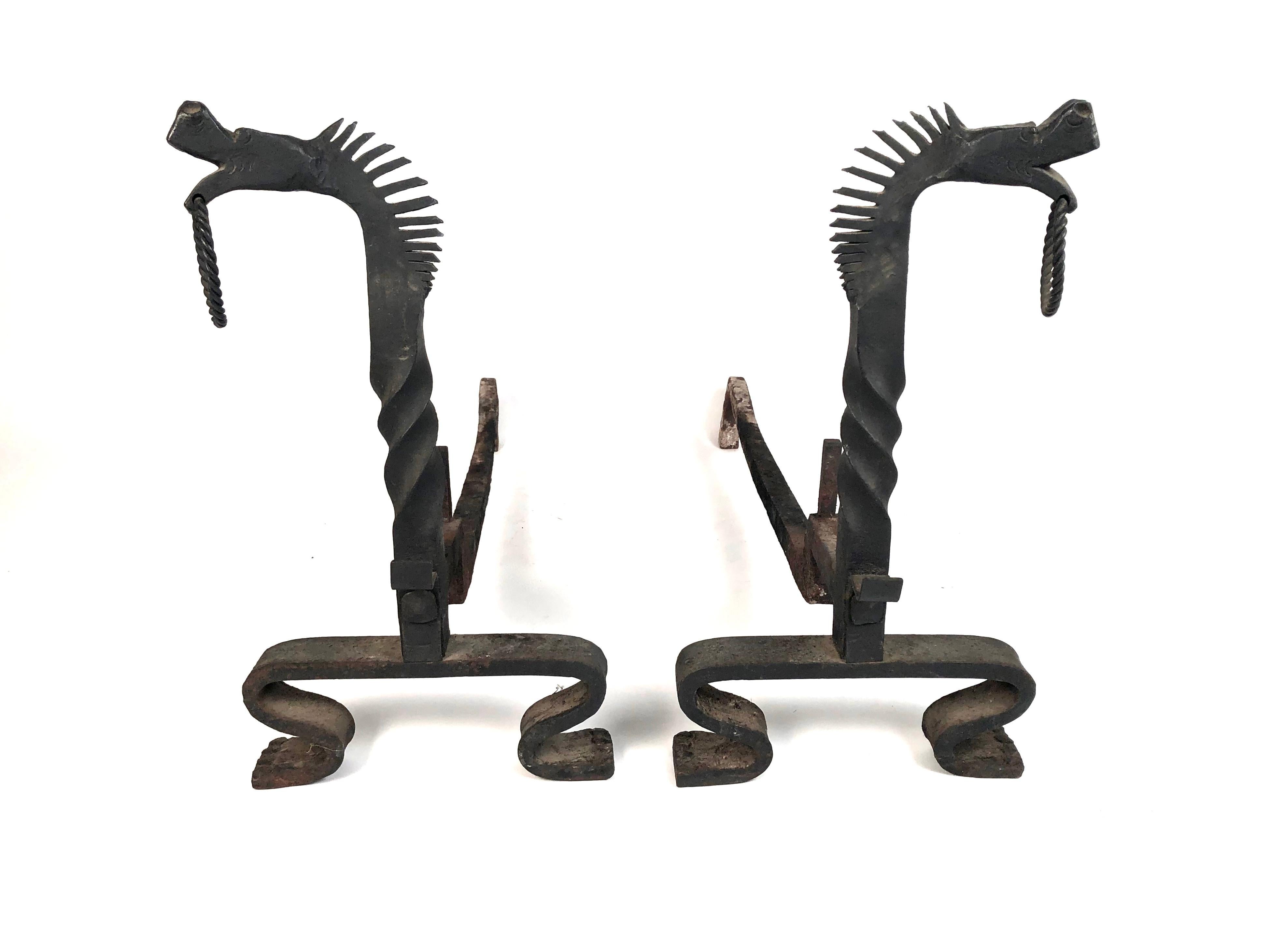 A fine quality Arts & Crafts period pair of wrought iron andirons, together with fireplace tools and jamb hooks, all beautifully modeled. The andirons have stylized dragon or horse (?) heads, with open mouths, each holding a ring, and lively manes.