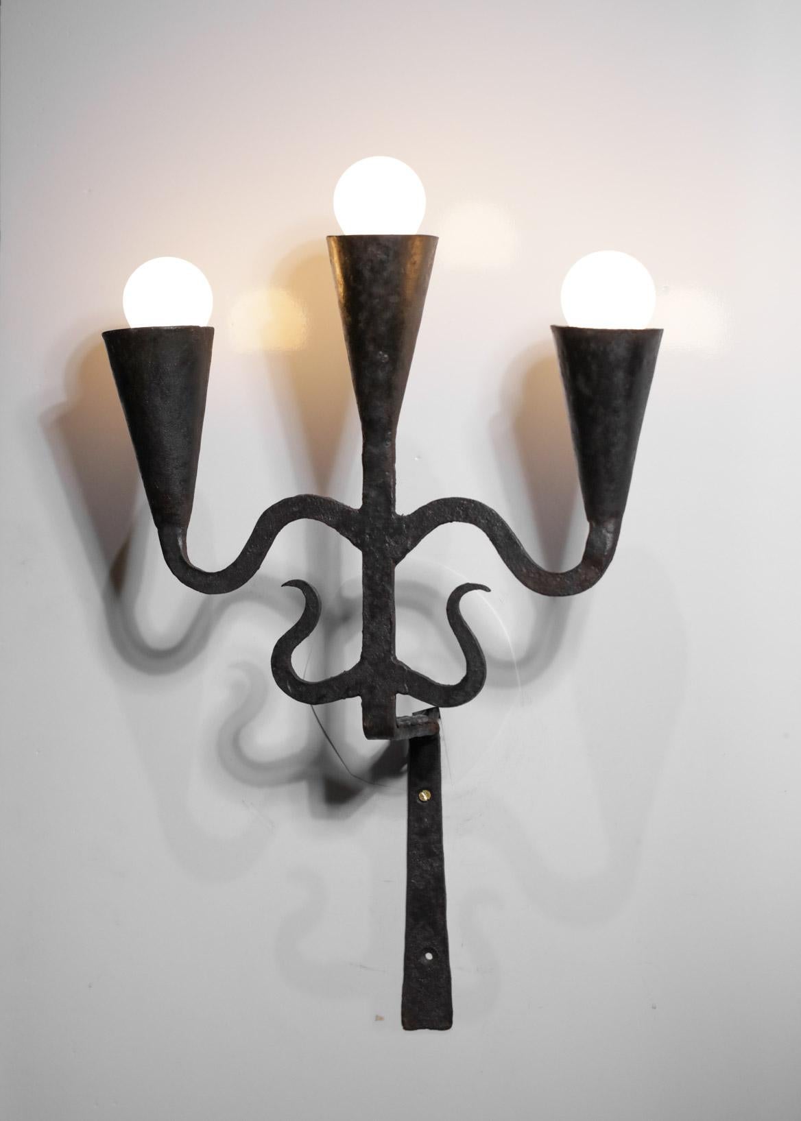 Pair of French wall sconces from the 50s in a brutalist style. Wrought iron structure in the style of Jean Touré and the Maroles workshops. Very nice patina of iron thanks to time, slight traces of use (see photos), three LED bulbs recommended type