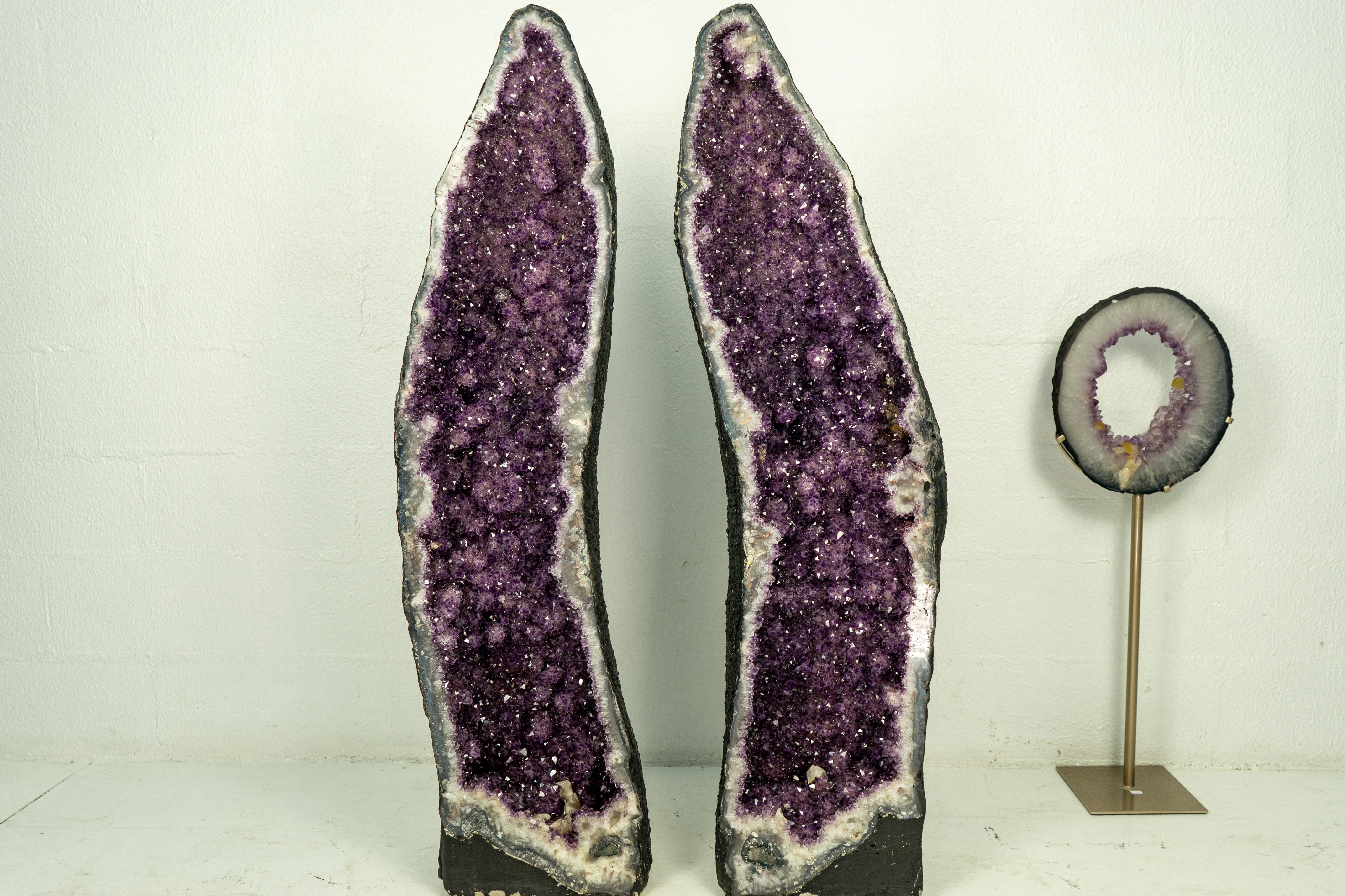 A book-matching pair of Amethyst Geodes bringing gorgeous characteristics as its beautiful aesthetics, shiny druzy, gorgeous color, X-Tall size, and formed as a cathedral-shaped geode. This is a natural artwork, ready to become a magnificent décor