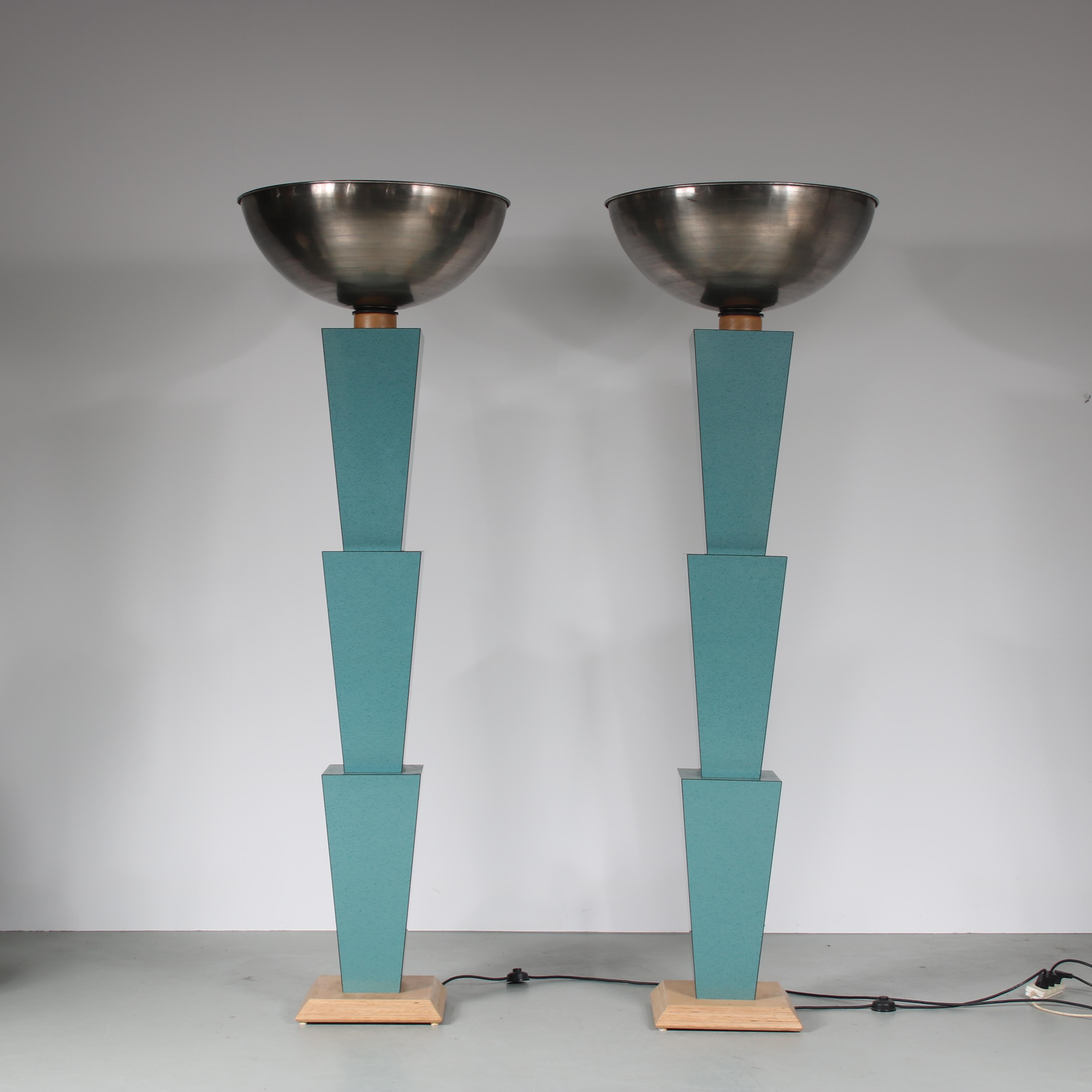An eye-catching pair of floor lamps in Memphis style, manufactured in Italy around 1980.

These unique lamps are made of wood, mostly green laminated. The base contains of multiple inverted trapezium shaped elements, which gives the pieces their