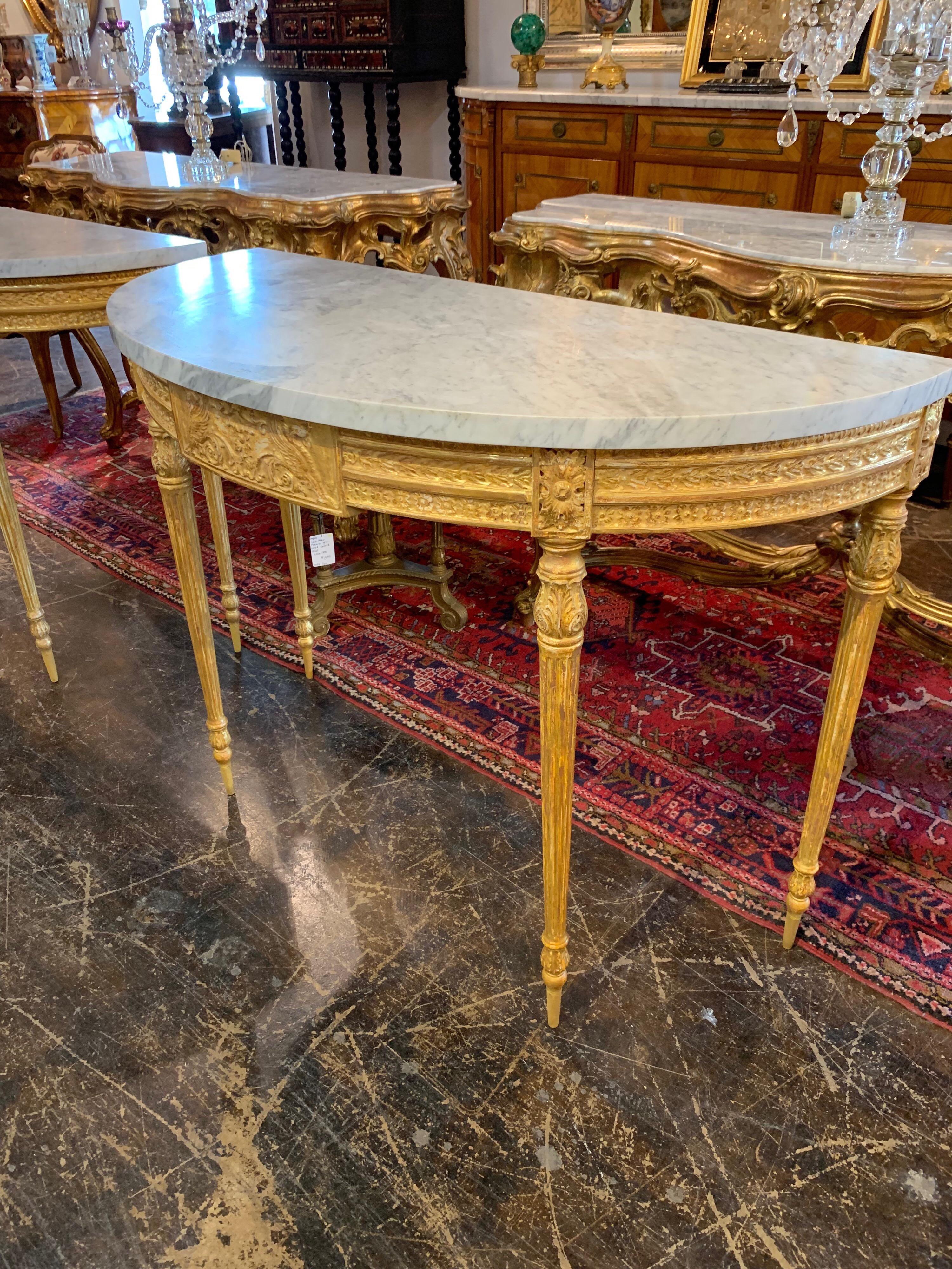 Exceptional pair of French Louis XVI style tightly carved giltwood demilune console tables with Carrara marble tops. Amazing carving and gilding on this pair. The marble is also beautiful. Truly exquisite!
