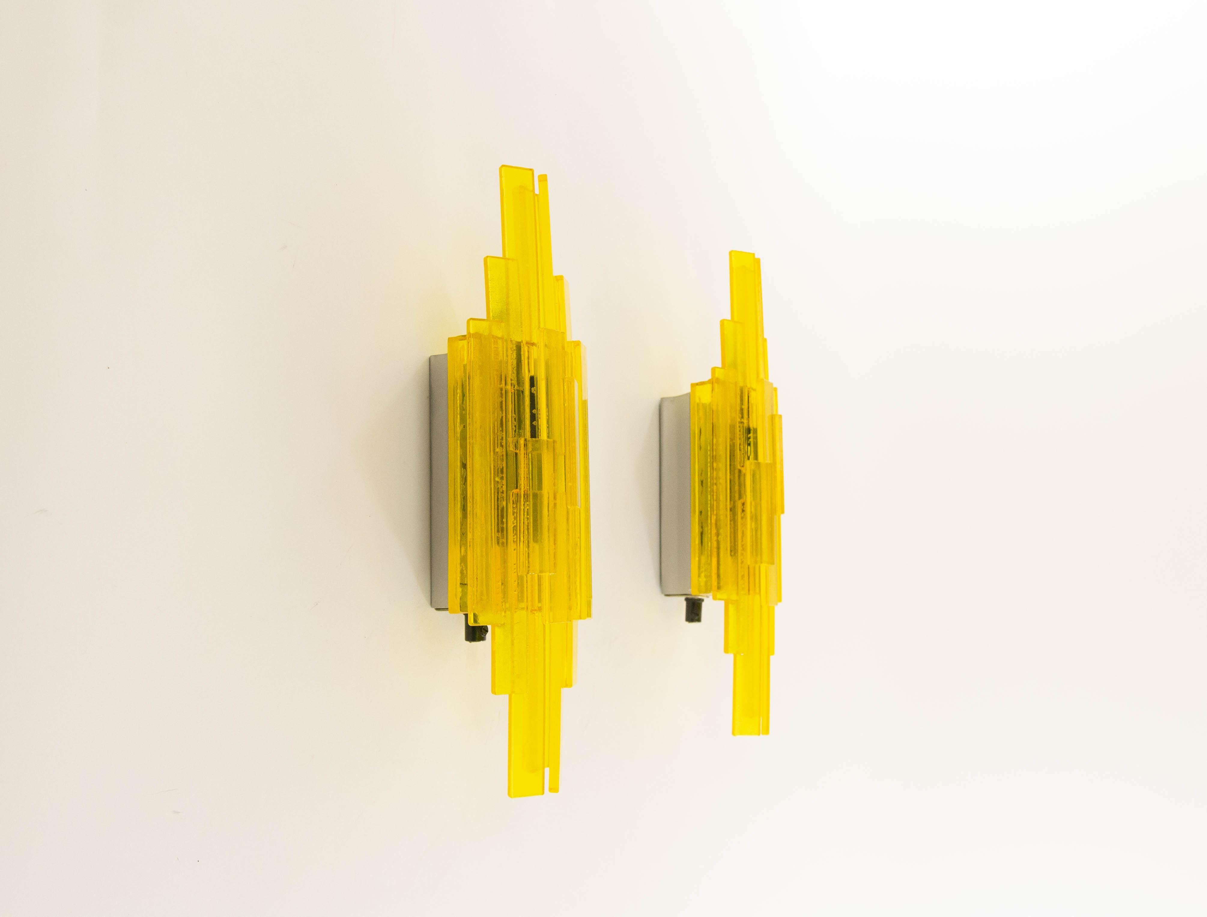 A pair of yellow handmade acrylic wall lamps. The sconces were designed by Claus Bolby and manufactured by his own company, Cebo Industri. By experimenting Bolby discovered a technique allowing him to introduce bubbles into the acrylic, which adds a