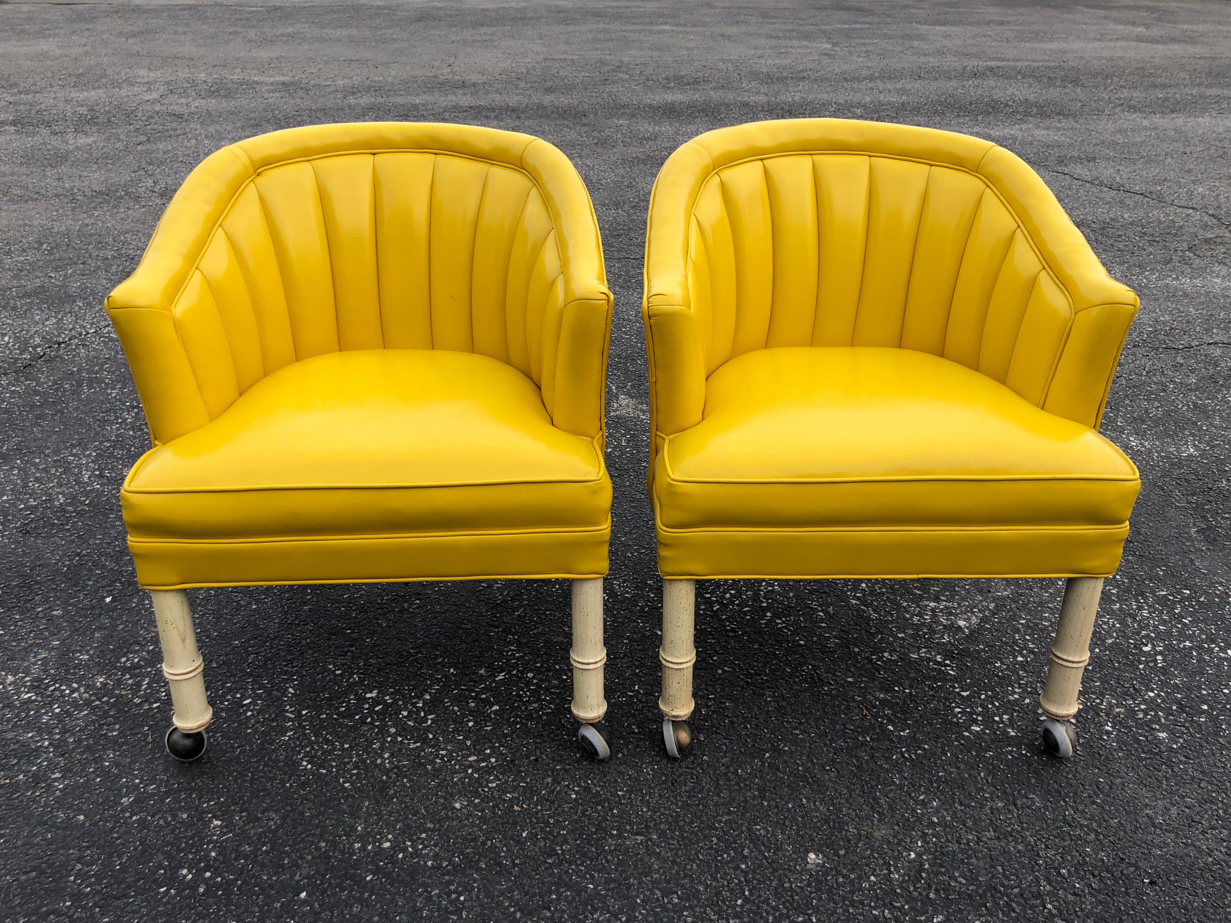 Pair of yellow channel back vinyl chairs on castors. Off-white faux bamboo legs with brass castors. Glam up that dressing room or home office with these crazy cool chairs. Measures: Total width is 25.25, total height is 29.75, total depth is 24.50,