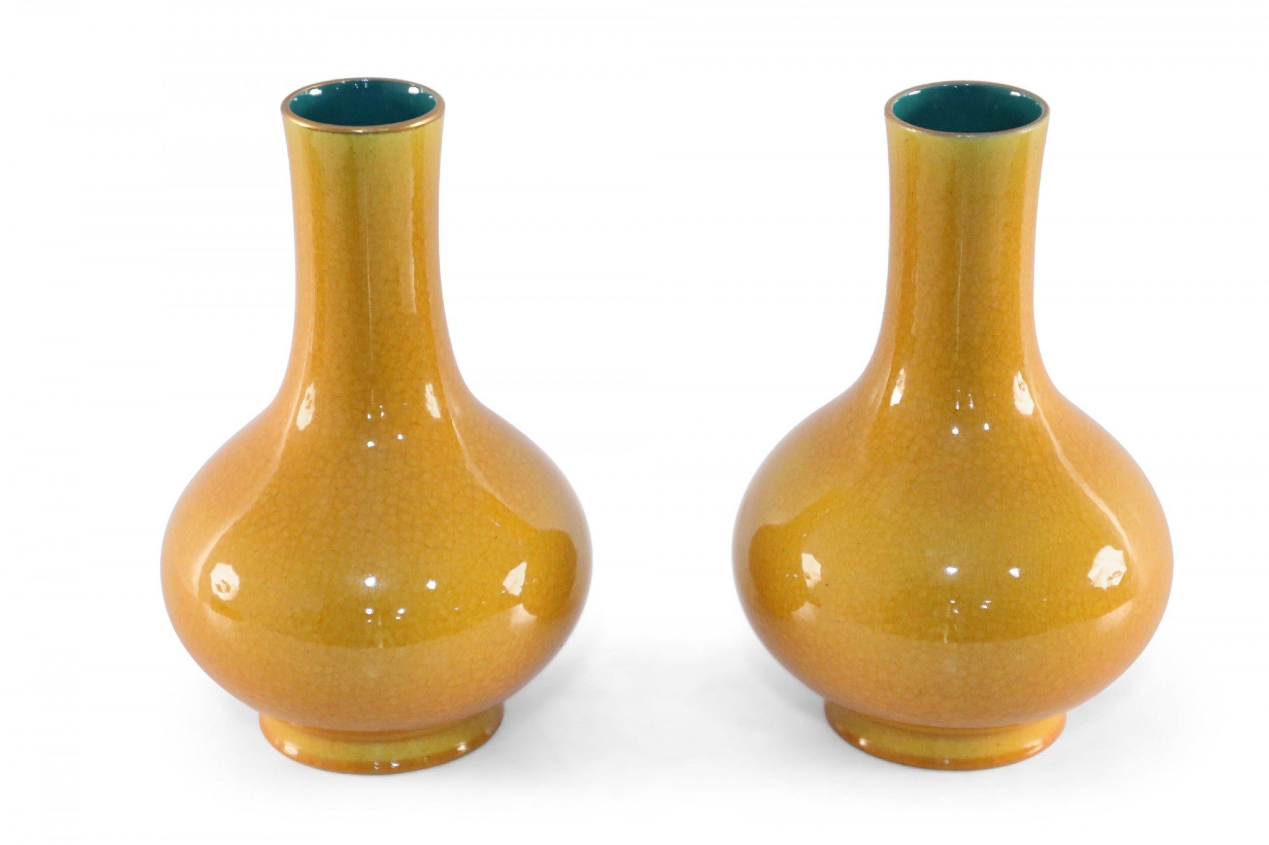 Pair of Chinese yellow, pear-shaped porcelain vases with crackled finishes, gold rims, and teal interiors (date mark on bottom, see photos) (priced as pair).
  
