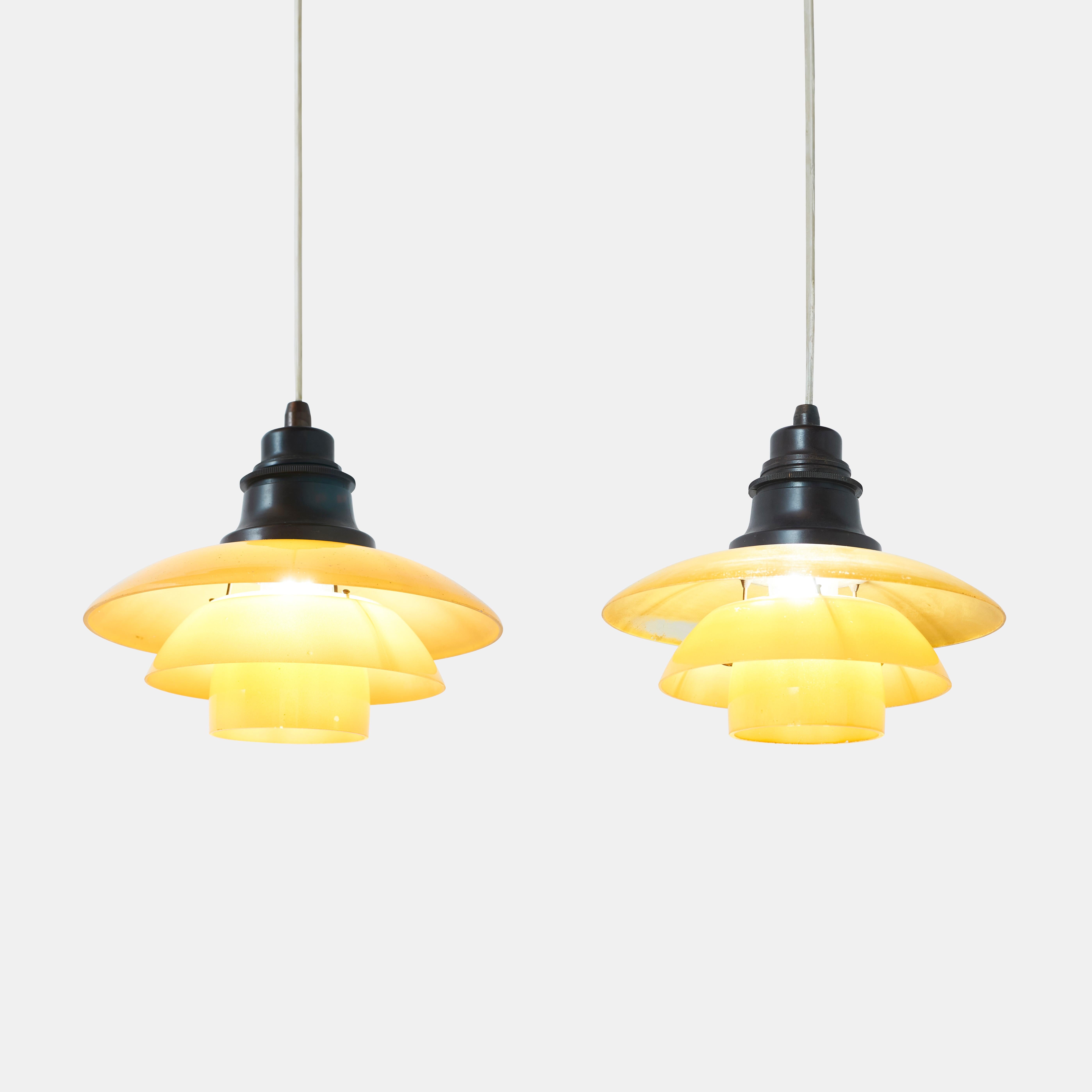 Pair of Yellow PH 2/2 pendents by Poul Henningsen
A pair of PH 2/2 pendant lamps for Louis Poulsen. Brown bakelite fixtures with yellow frosted glass shades.

There are some abrasions to the yellow frosted glass on both examples. 
No chips on