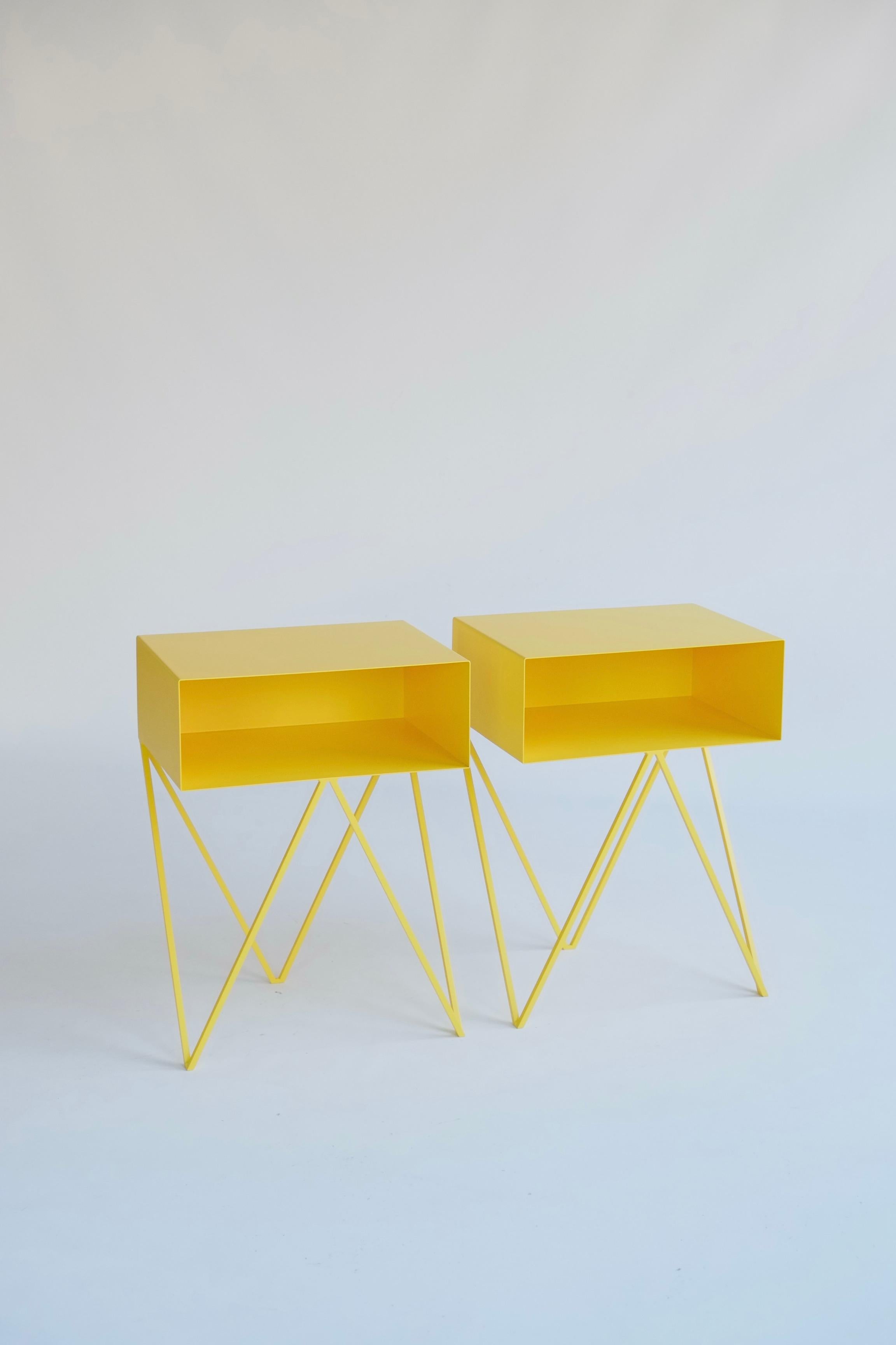 Une belle paire de tables de chevet en Robot jaune. La table d'appoint Robot comporte une étagère ouverte sur des pieds en zig-zag. Un design amusant et fonctionnel en acier massif, recouvert d'un revêtement en poudre de couleur jaune. Les lignes
