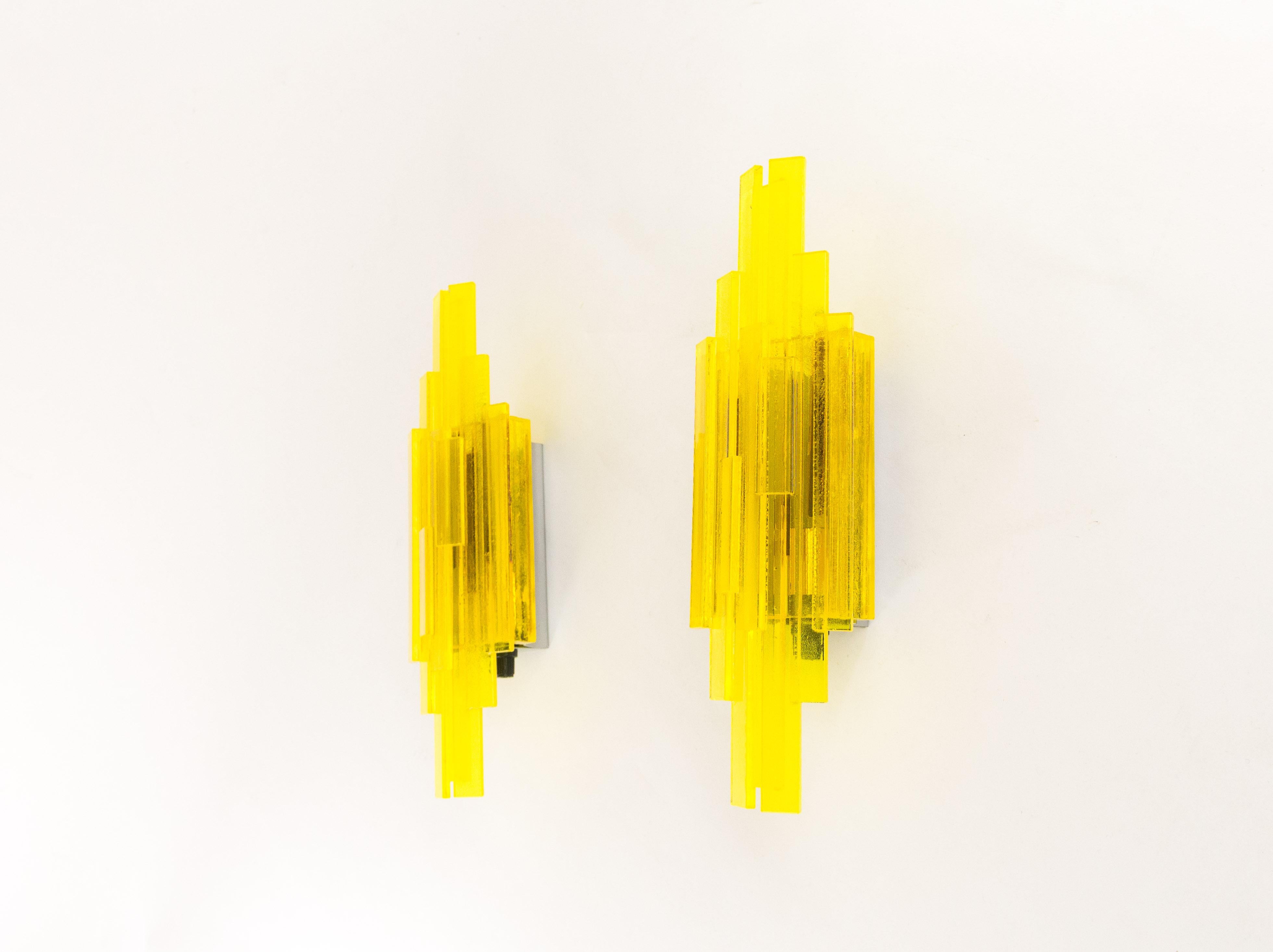 A pair of yellow handmade acrylic wall lamps. The sconces were designed by Claus Bolby and manufactured by his own company, Cebo industry. By experimenting, Bolby discovered a technique allowing him to introduce bubbles into the acrylic, which adds