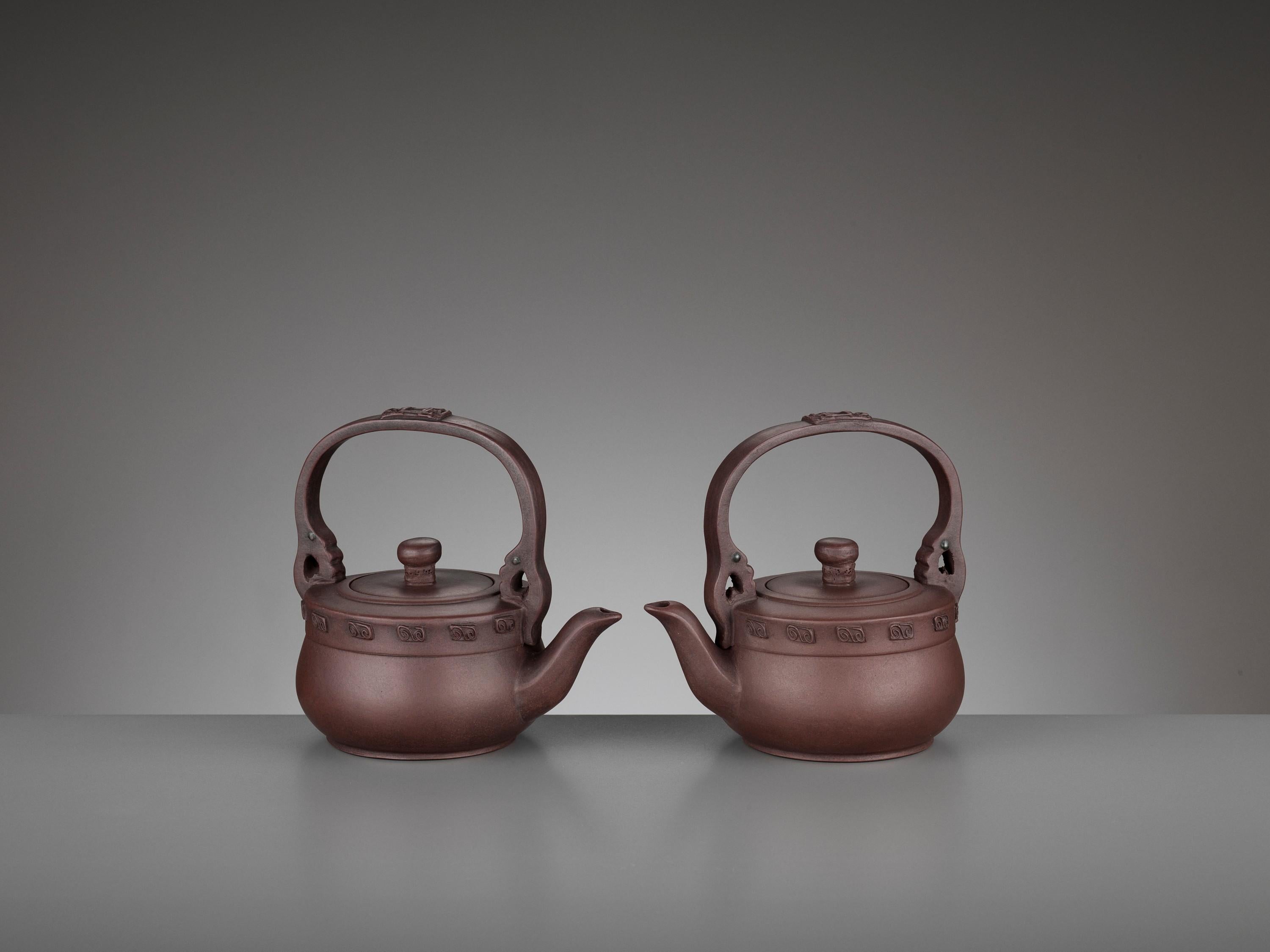 Pair of Yixing teapots, Signed Qian Hongxian, China, 20th century

Each with an arched loop handle above the cover decorated with a geometric design in relief, an elegantly curved spout, and a circular cover with a central pierced knop, the