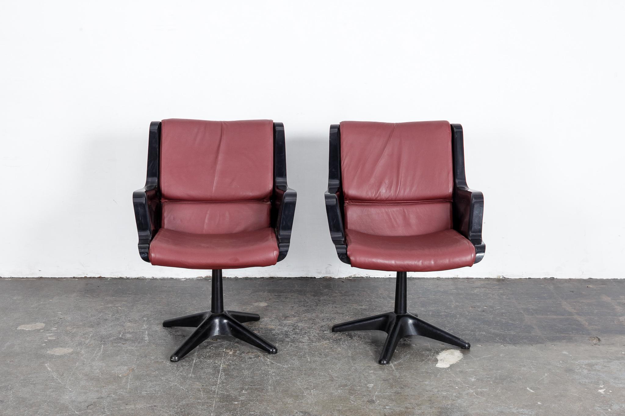 Pair of Yrjo Kukkapuro swivel side or desk chairs in black molded plastic with newly upholstered wine colored leather cushion.  Made in Finland by Haimi. .