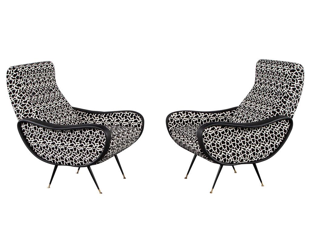 Pair of Zanuso style lounge chairs in black and white. Iconic Zanuso styling, recently upholstered in a unique black and white geometric design with accenting black leather arms. Completed with sleek satin black legs capped with brass. In excellent