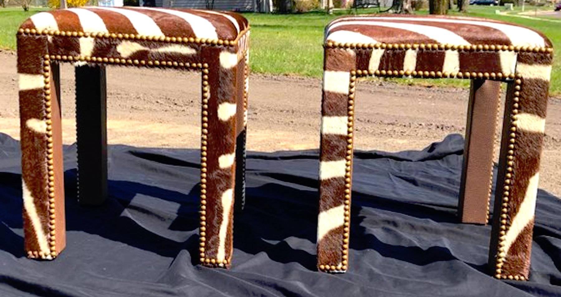 Pair of zebra hide parsons benches, each one bronze nail head trim and leather interior legs.