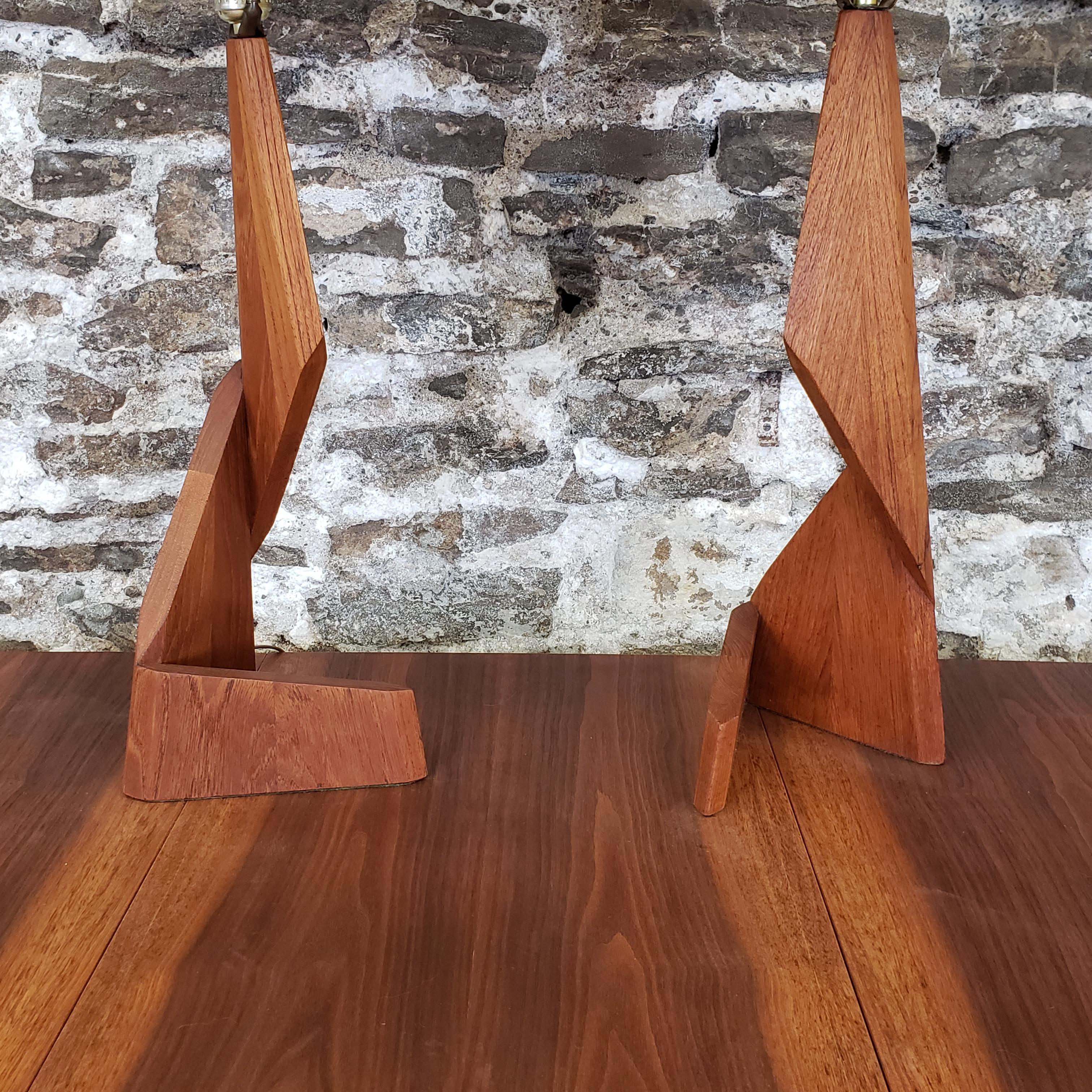 Pair of uniquely designed 'zig zag' teak table lamps from the Danish Mid-Century Modern era. Amazing craftsmanship throughout, featuring sculpted geometric solid teak base's with conical fabric shades.