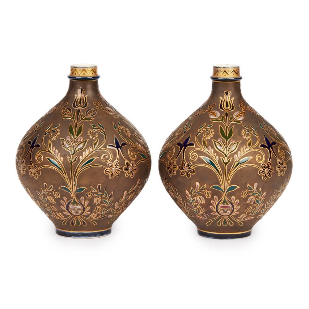 A rare and exquisite pair of Hungarian Zsolnay Pecs Persian floral design vases. The ceramic vases are of rounded bulbous bottle or flagon shape standing on a narrow rounded foot and with a narrow bottle shaped top. The vases are decorated in raised