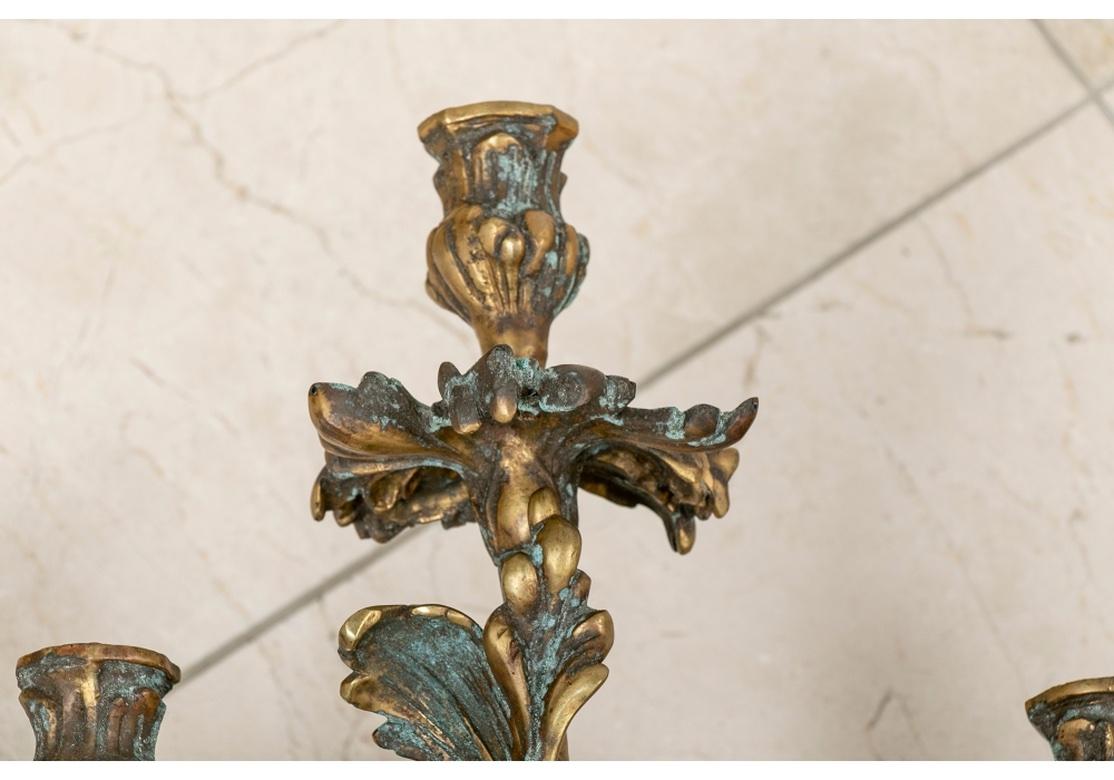 A pair of large and heavy five arm antique bronze candle sconces with elaborate sinuous leafy arms, back and a tall top socket. The Pair retain the original Copper tubing presumably once utilized for gas lighting. Non-electrified. 
Measures: height