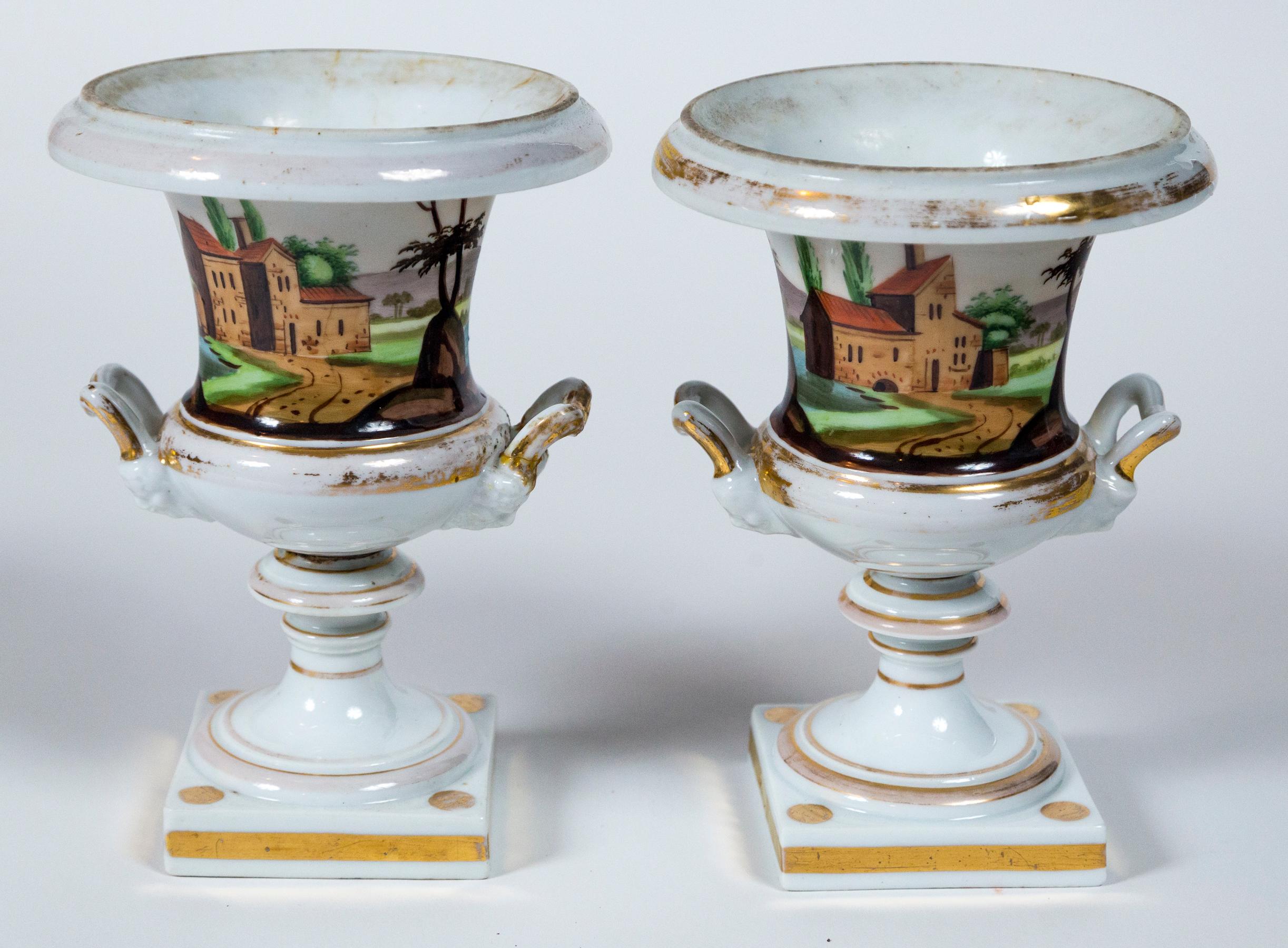Pair Old Paris porcelain urns, France, 19th Century. Hand-painted classical form urns. A different landscape scene on each urn. Lovely colors with gold trim.