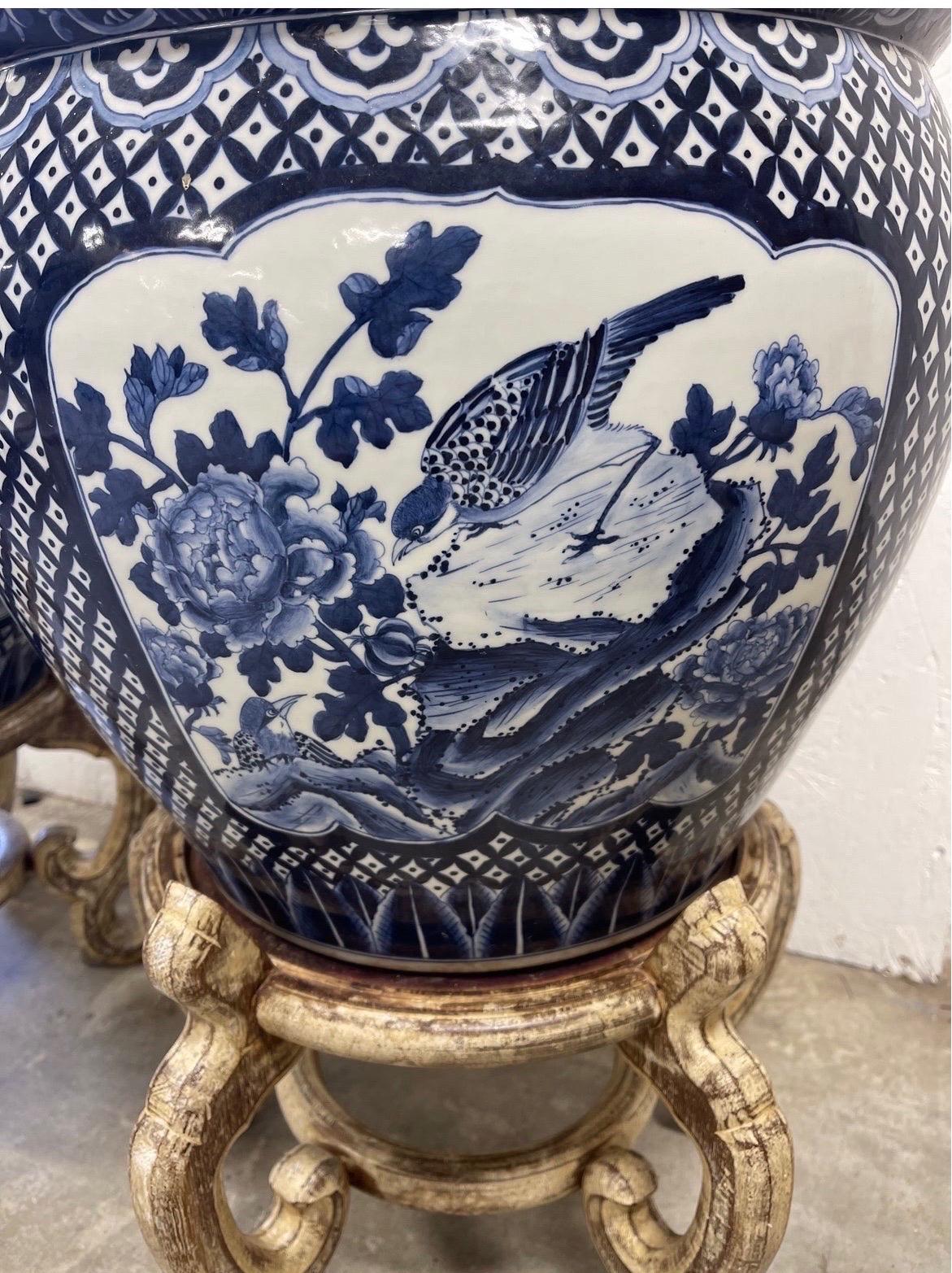 Pair of quality chinese export style blue and white jardineres on distressed wood stands. Decorated with foliate and bird windows to each.
Measures: Planters 13” H x 16” W
Stands 10” H x 11” W.