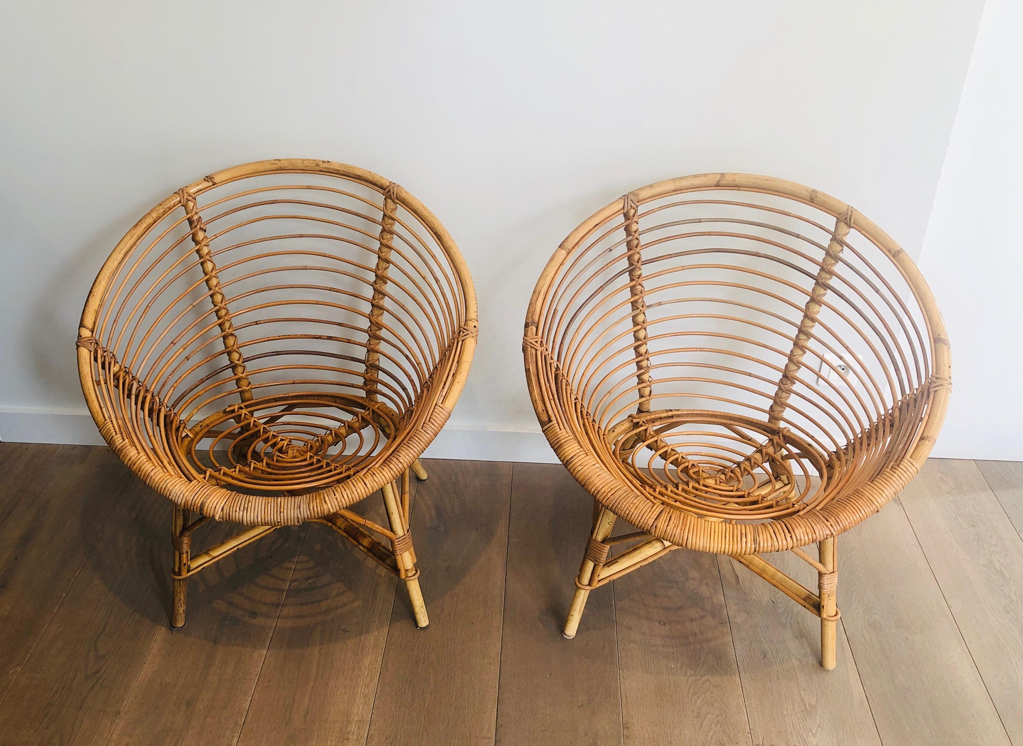 This very nice pair of armchairs is made of rattan. This round shape is unusual and make these armchairs very special and decorative. This is a French work. Circa 1970