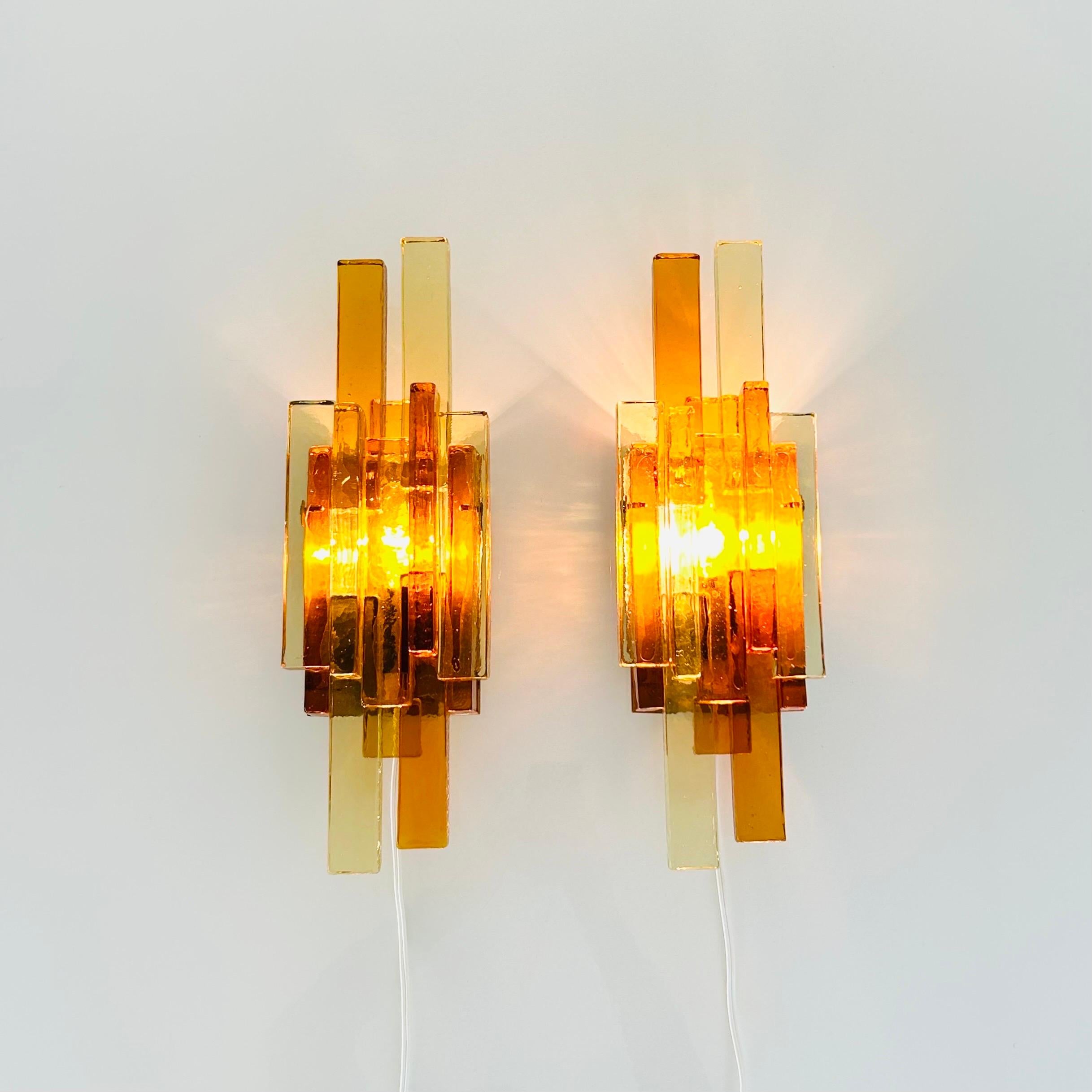 Introducing a stunning pair of vintage sconces by the renowned Danish designer Svend Aage Holm Sørensen. These sconces are a true masterpiece of Danish modern lamp art, featuring thick yellow and amber glass bricks mounted on a brass lacquered wall