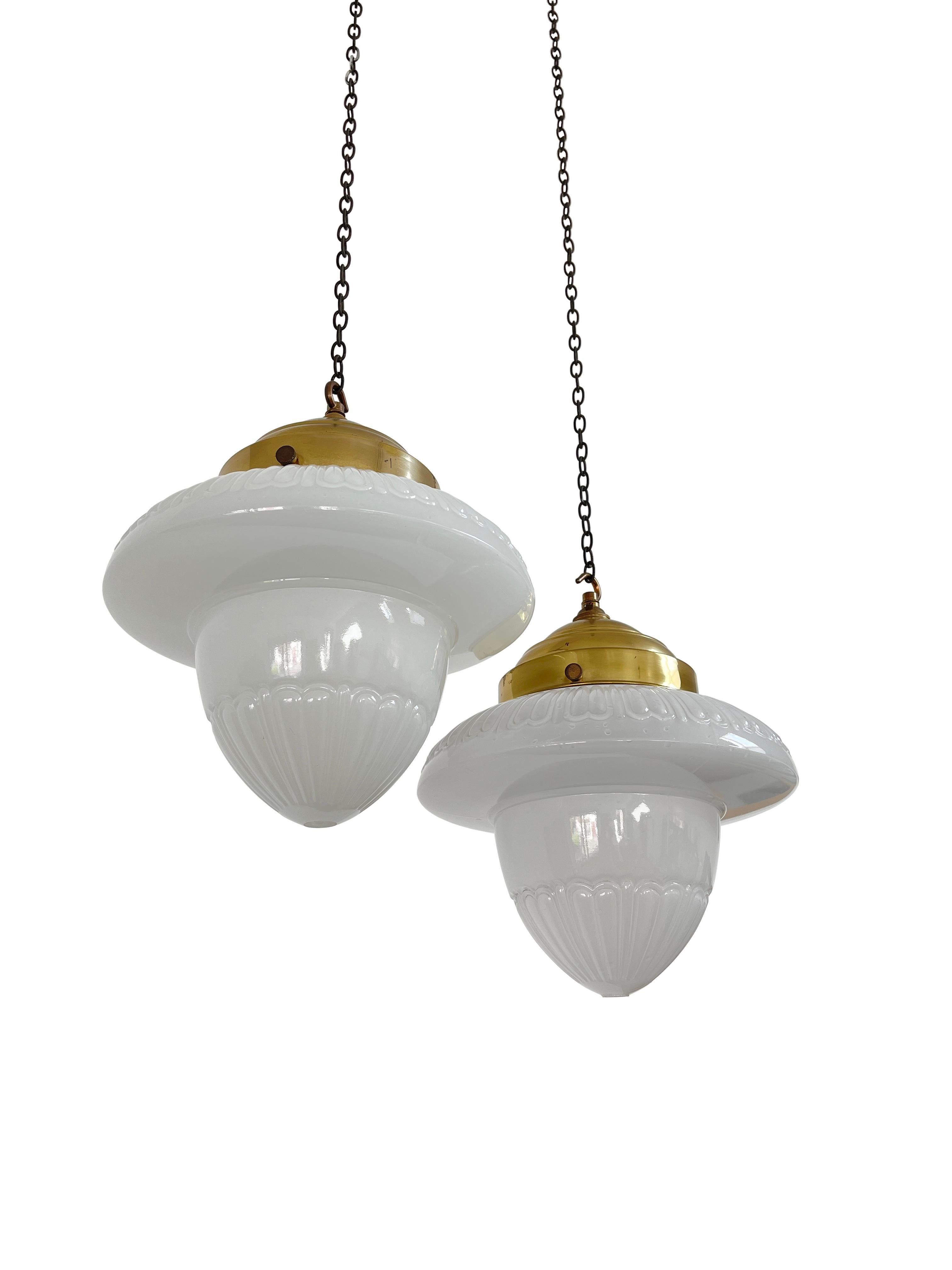 - A wonderful pair of acorn opaline pendant lights, English, Early Twentieth Century.
- Heavy quality glass shades with intricate detail and pattern, small open holes to the underneath, large round hooked brass galleries.
- Wear commensurate with