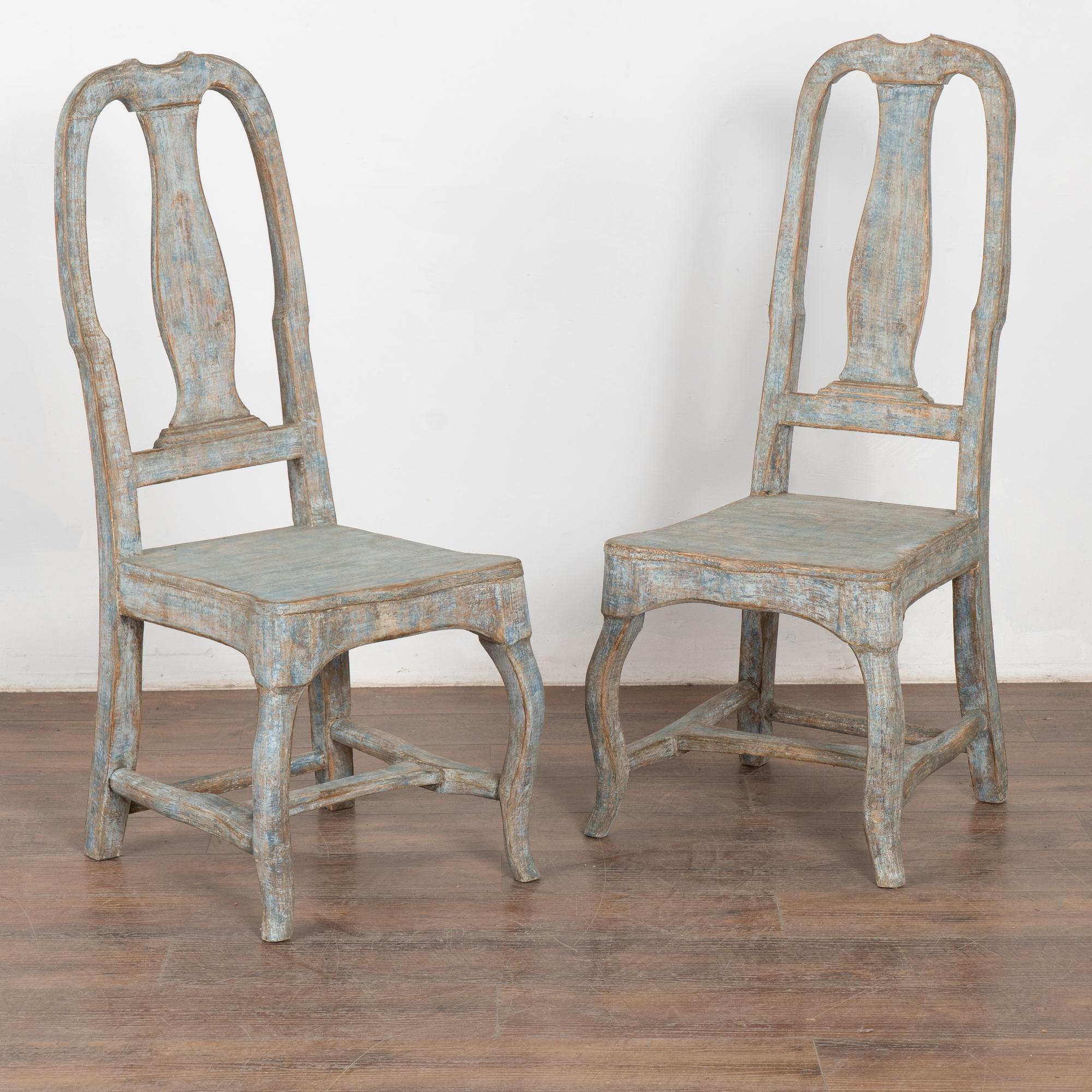 C'est la finition originale peinte en bleu qui attire l'attention sur cette paire de chaises d'appoint rococo à haut dossier provenant de Suède. 
La peinture bleue d'origine avec des traces de blanc a été légèrement grattée, révélant la patine