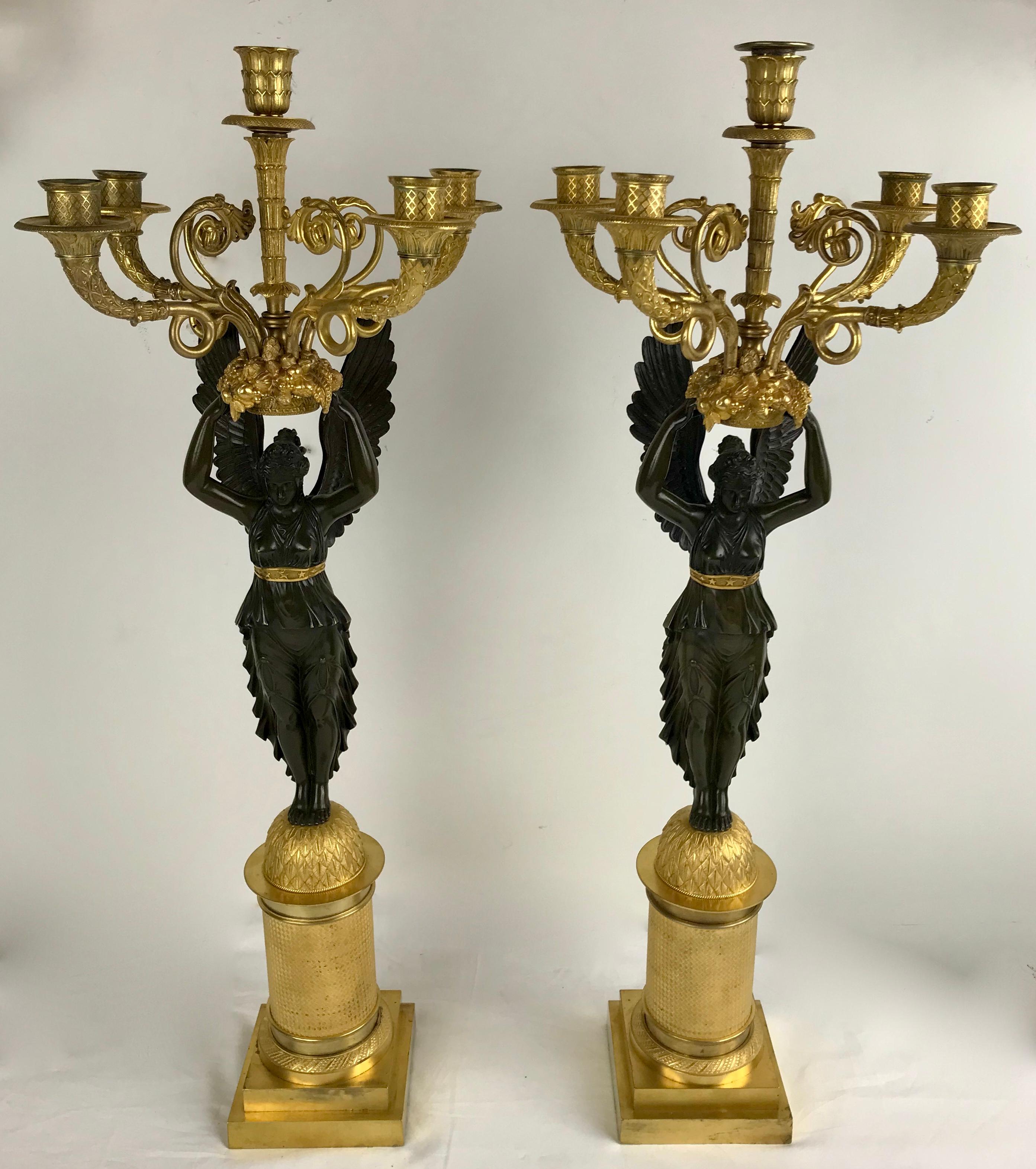 This fabulous pair of Charles X ormolu and patinated bronze five light candelabra are signed Meignan and date from the early 19th Century.
The scrolled arms issuing from a gilt bronze basket held aloft by a figure of Winged Victory on a domed