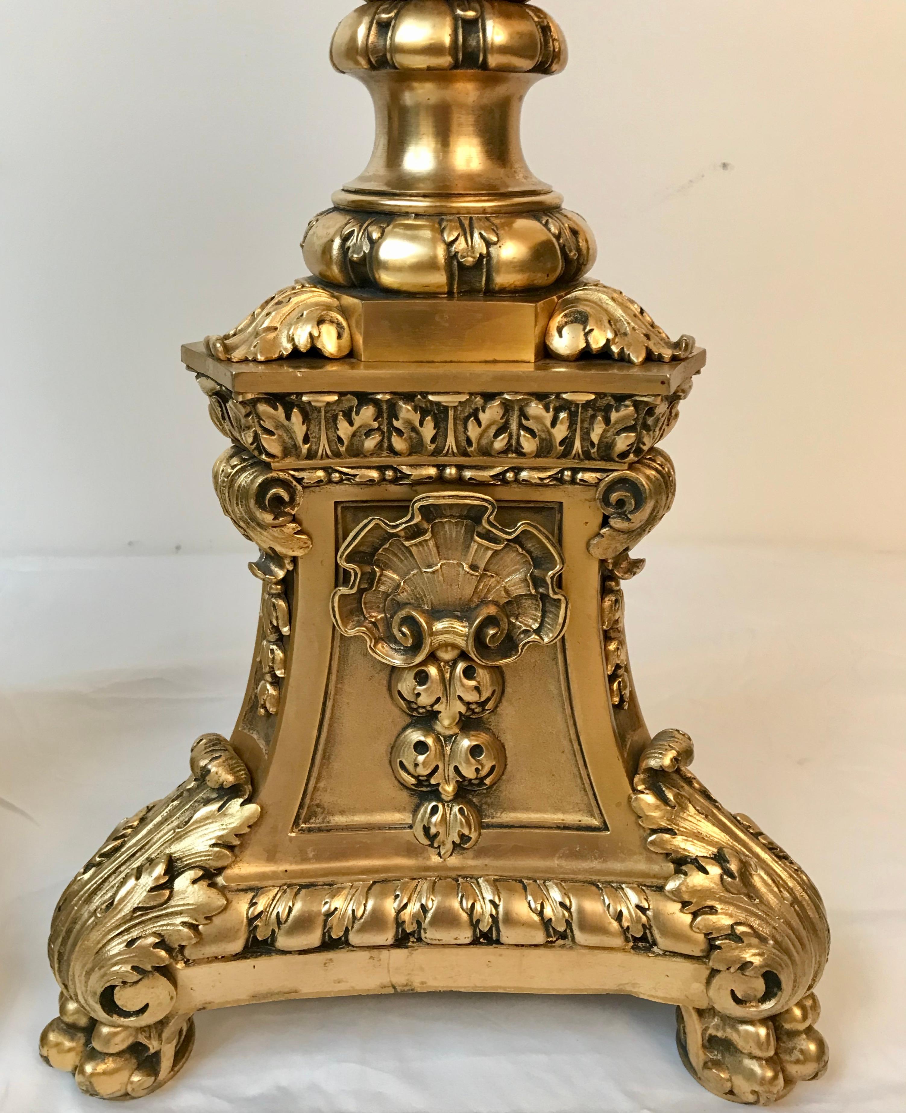 This large and impressive pair of cast and chased gilt bronze andirons are of the finest quality. The triangular plinth bases with canted corners rest on lion paw feet, The andirons feature classical motifs including bellflowers, shells, and