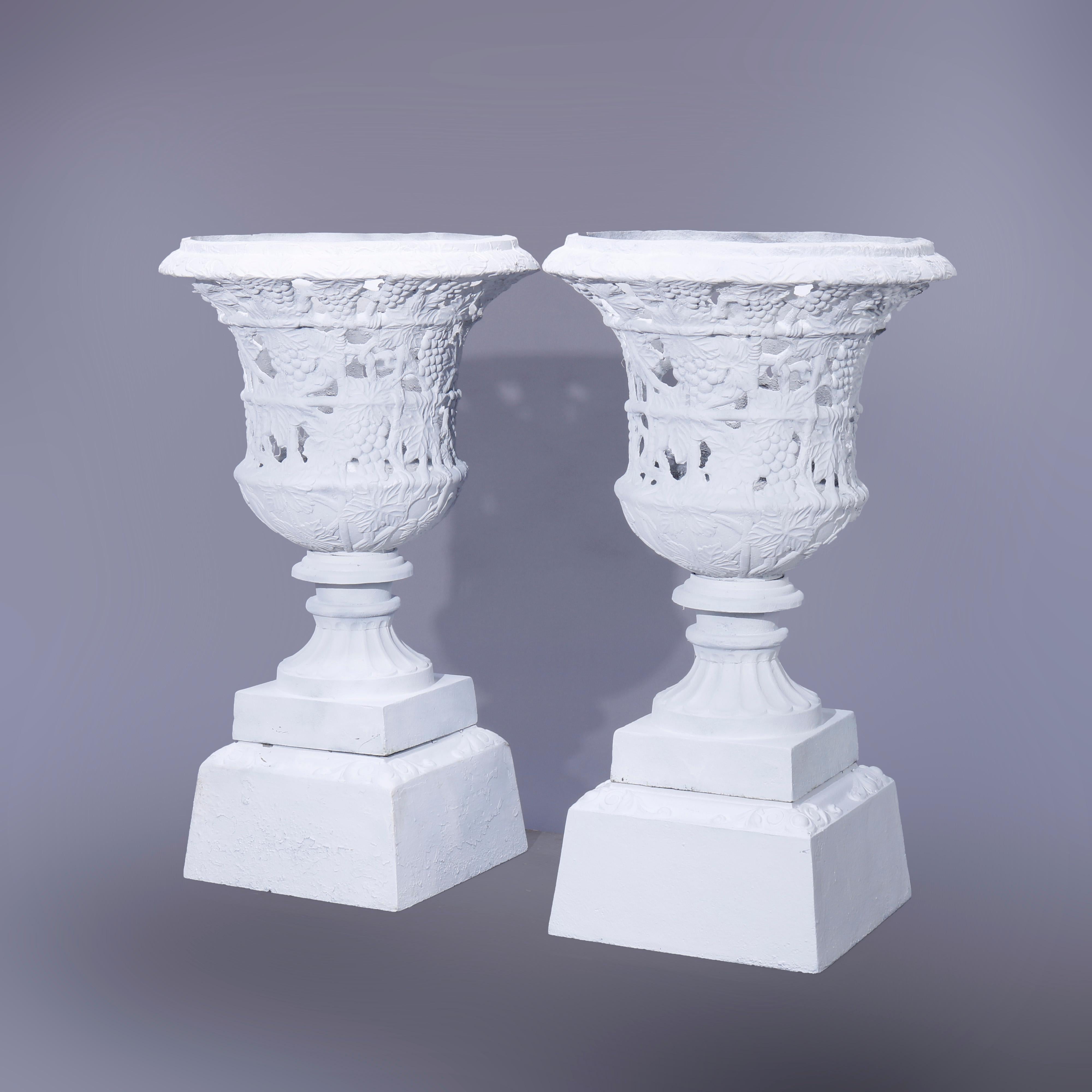 A pair of large garden urns offer cast iron construction with reticulated grape and leaf pattern raised on square plinth bases, newer paint, 20th century

Measures - 41''H x 24''W x 24''D.