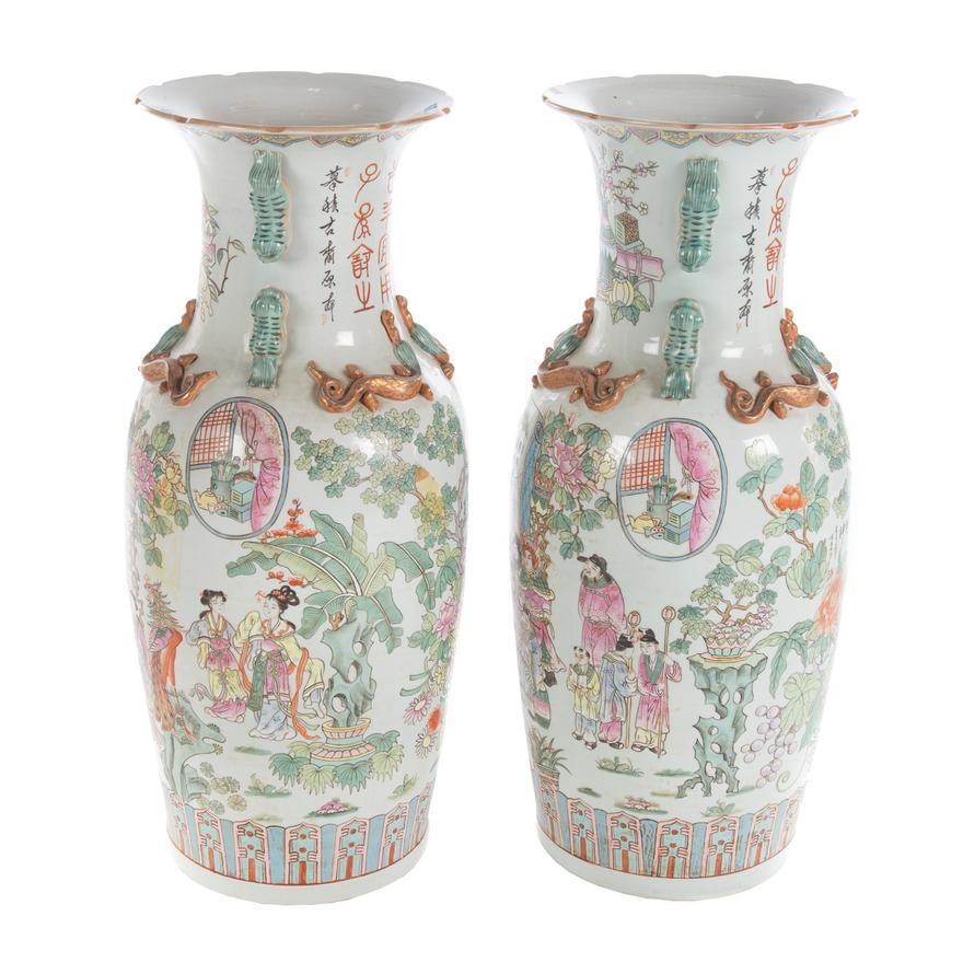 Pair of palace sized porcelain vases in the Famille Rose style with sylized dragons at the shoulder and fu dog handles, and enameled court scenes and landscapes.