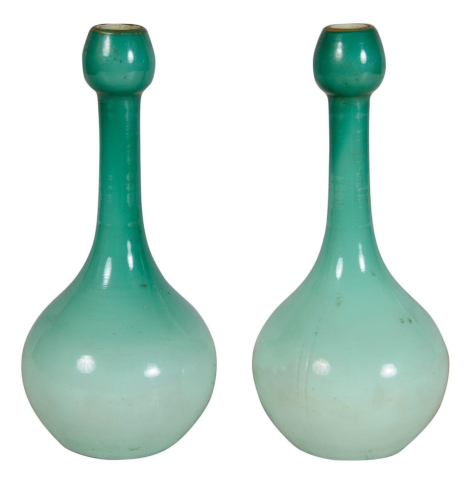 This pair of  exquisite late 19th-century Bohemian Peachblow vases showcase a stunning gradient of soft green hues. Their elegant, elongated forms feature intricately designed floral motifs, beautifully accented with gold leaf detailing. The