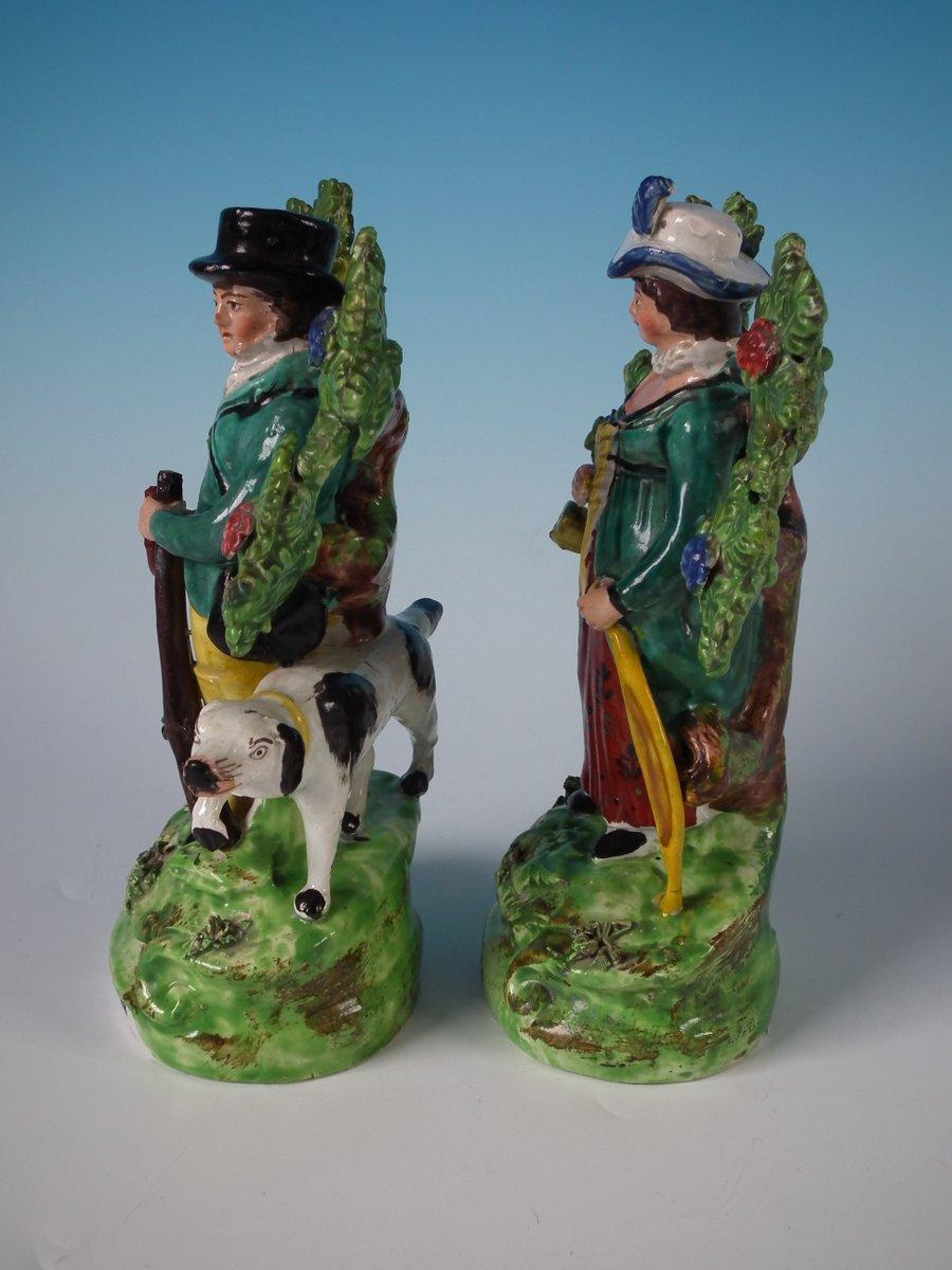 Pair of Staffordshire pottery pearlware bocage figures with a hunting theme which feature a huntsman with his dog and a female archer, stood on shaped bases. The pieces are titled, 'Sportsman' & 'Archer' to the fronts. Decorated 'in the round' -