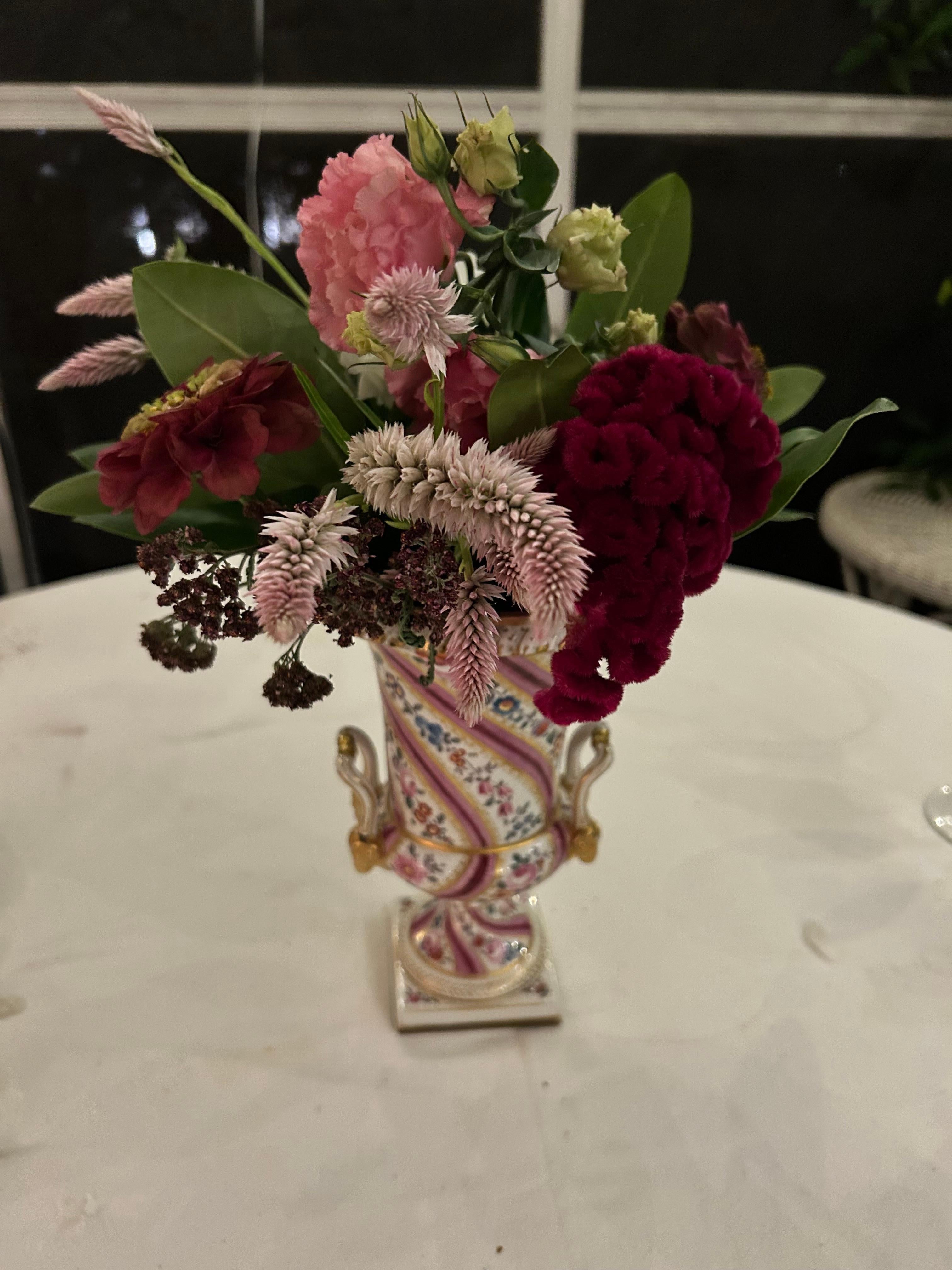 Paar rosa Blumen und vergoldetes Porzellan gemalt Urnen. Paar Urnen mit leuchtend rosafarbenen, maulbeerfarbenen und fuchsiafarbenen Bändern, die sich mit üppigen Blumenranken auf dem zweiteiligen Korpus mit Henkeln aus Widderköpfen abwechseln. In