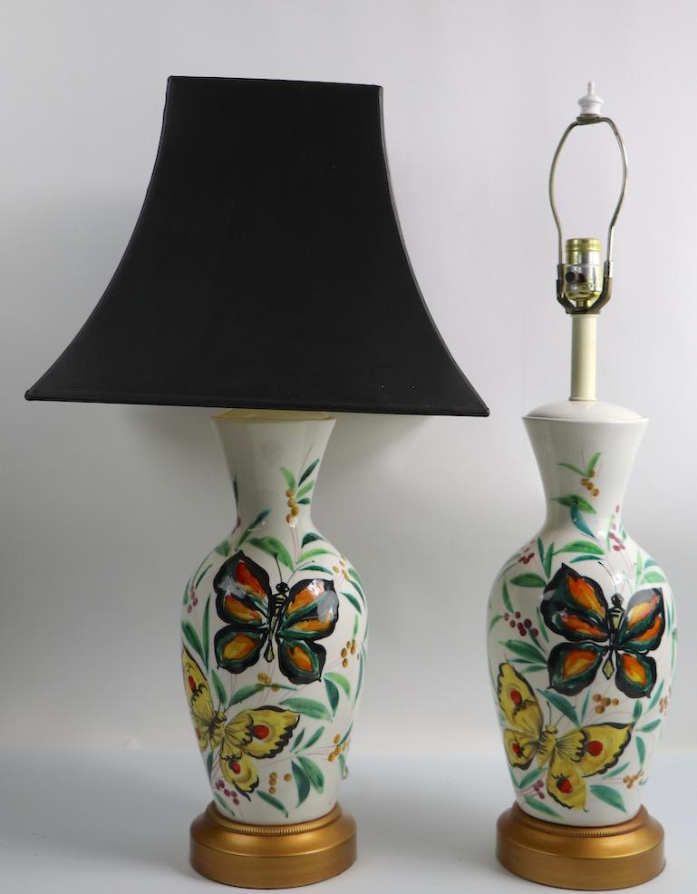 Pair of porcelain table lamps having white bodies with hand painted butterflies, and foliate decorations. Classic late midcentury optimistic style, likely Italian in origin. Fun and playful while still being sophisticated and chic. Original, clean,