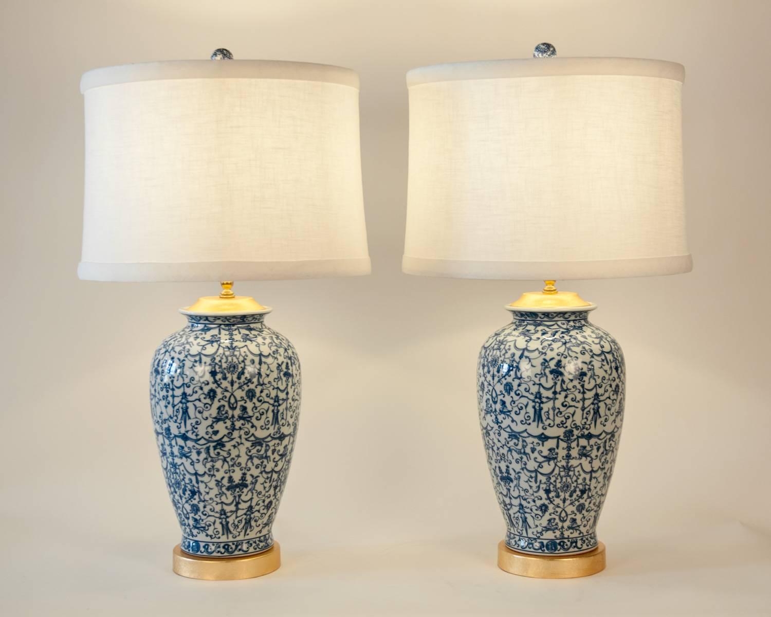 A pair of porcelain table or task lamps with gold-plated top and wooden gold-plated base. Excellent working condition. Each lamp measure about 32 inches high and 10 inches body diameter. Each lamp comes with a round linen exterior, silk interior