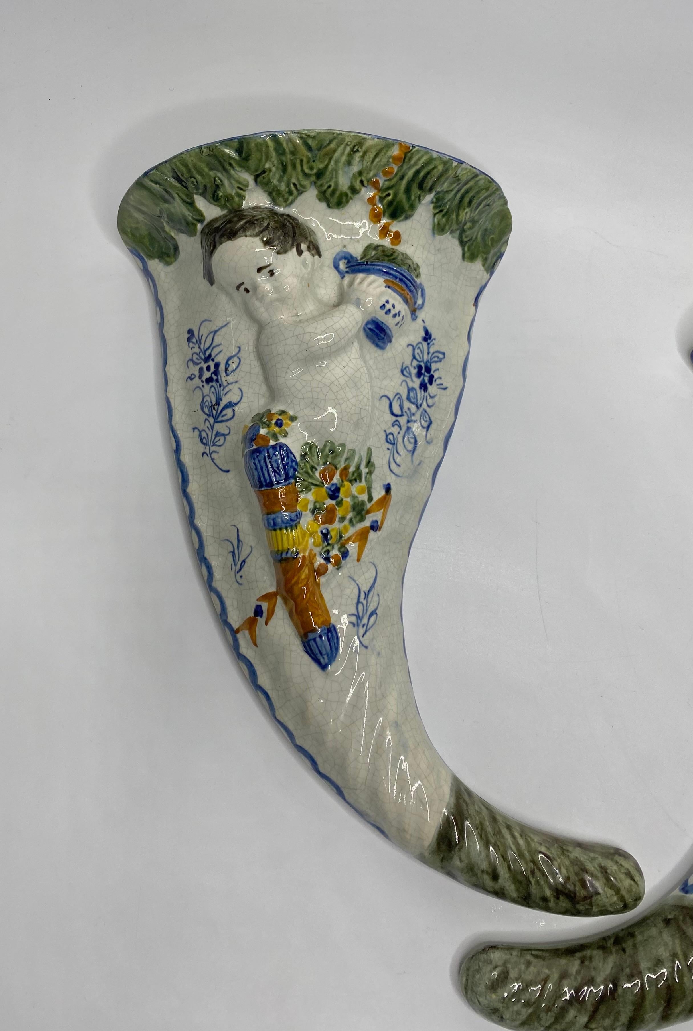 Pair of large English Prattware pottery wall pockets, c. 1810. The cornucopia shaped wall pockets, moulded with Cupid with a quiver of arrows suspended from swags of flowers in high relief, on a wrythen ground. On one pocket, Cupid drinks from a