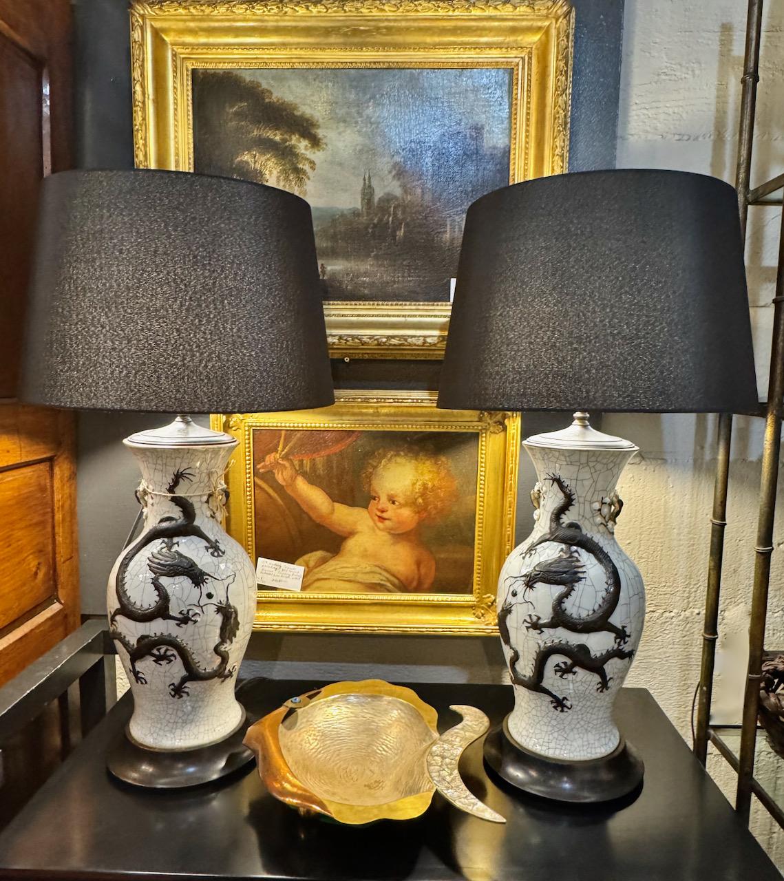 Il s'agit d'une très grande et étonnante paire de vases à dragon et à perle flamboyante en glaçure céladon pâle de Chine de la fin du XIXe siècle, qui ont été adaptés à des lampes avec des raccords à double douille. Les dragons bien sculptés sont