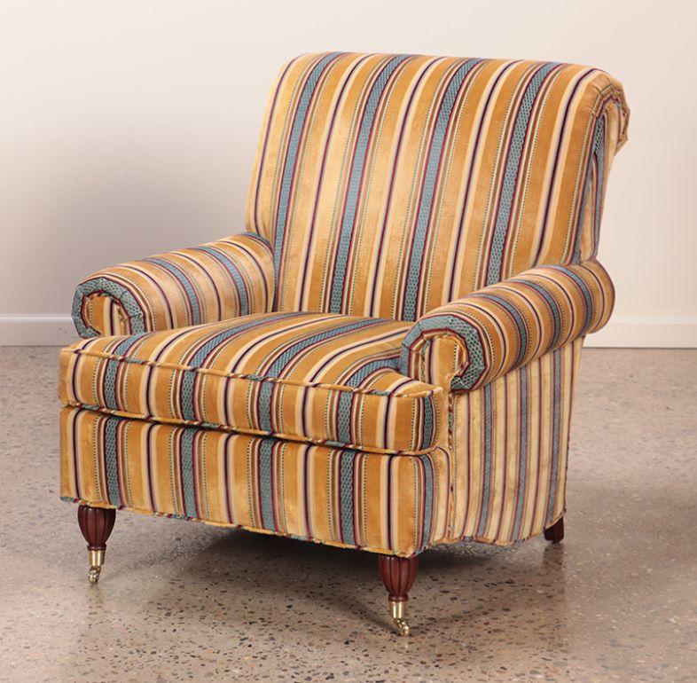 Pair quality upholstered club chairs in striped fabric having brass castors in the manner of Howard and sons. Labeled Charles Stewart Co.